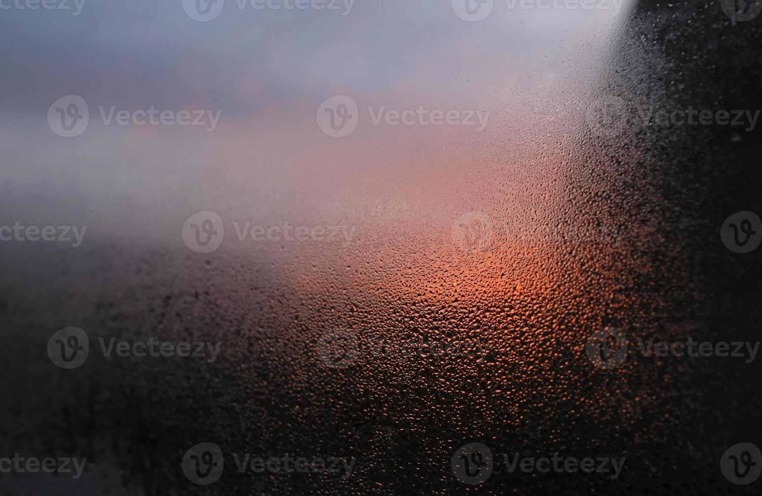 gros plan de condensation sur une fenêtre avec un coucher ou un lever de soleil en arrière-plan photo