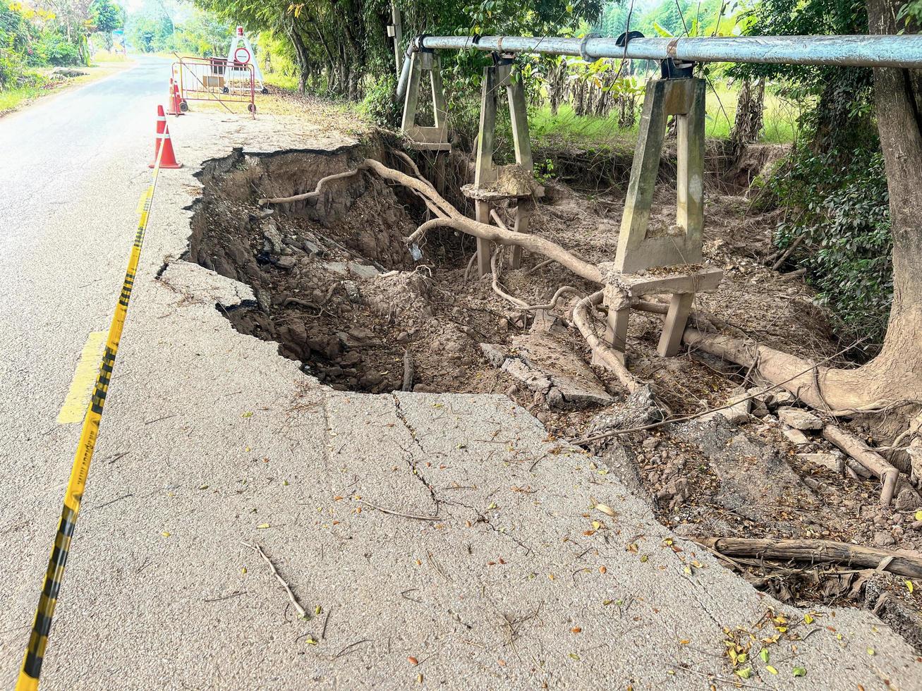 la route asphaltée s'est effondrée et les fissures sur le bord de la route, le glissement de terrain de la route s'estompe avec le cône de la route causé par l'érosion de la rivière photo