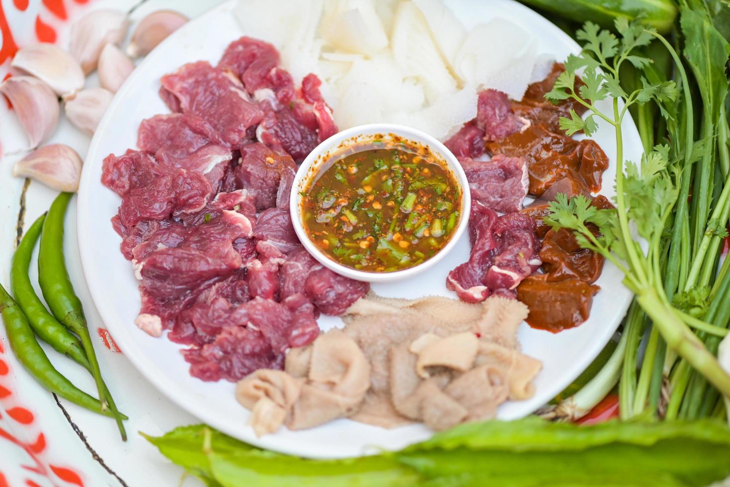 tranche de boeuf cru sur assiette avec légumes frais et sauce épicée, viande de sashimi de boeuf - salade de boeuf crue épicée à la thaïlandaise salade de viande hachée épicée photo