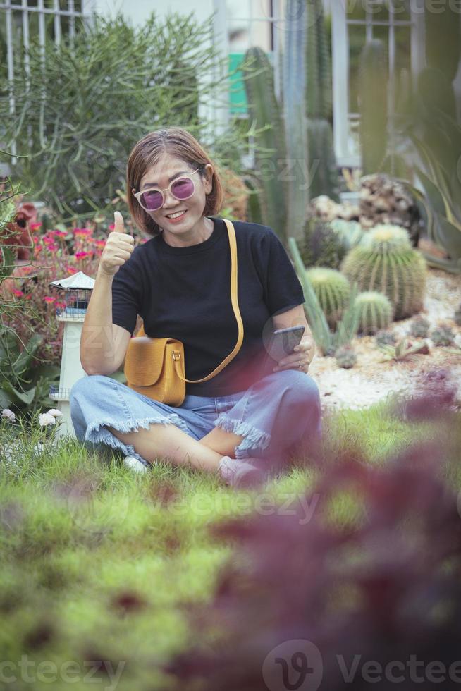 femme asiatique à pleines dents souriant avec bonheur assis dans le jardin de la maison photo