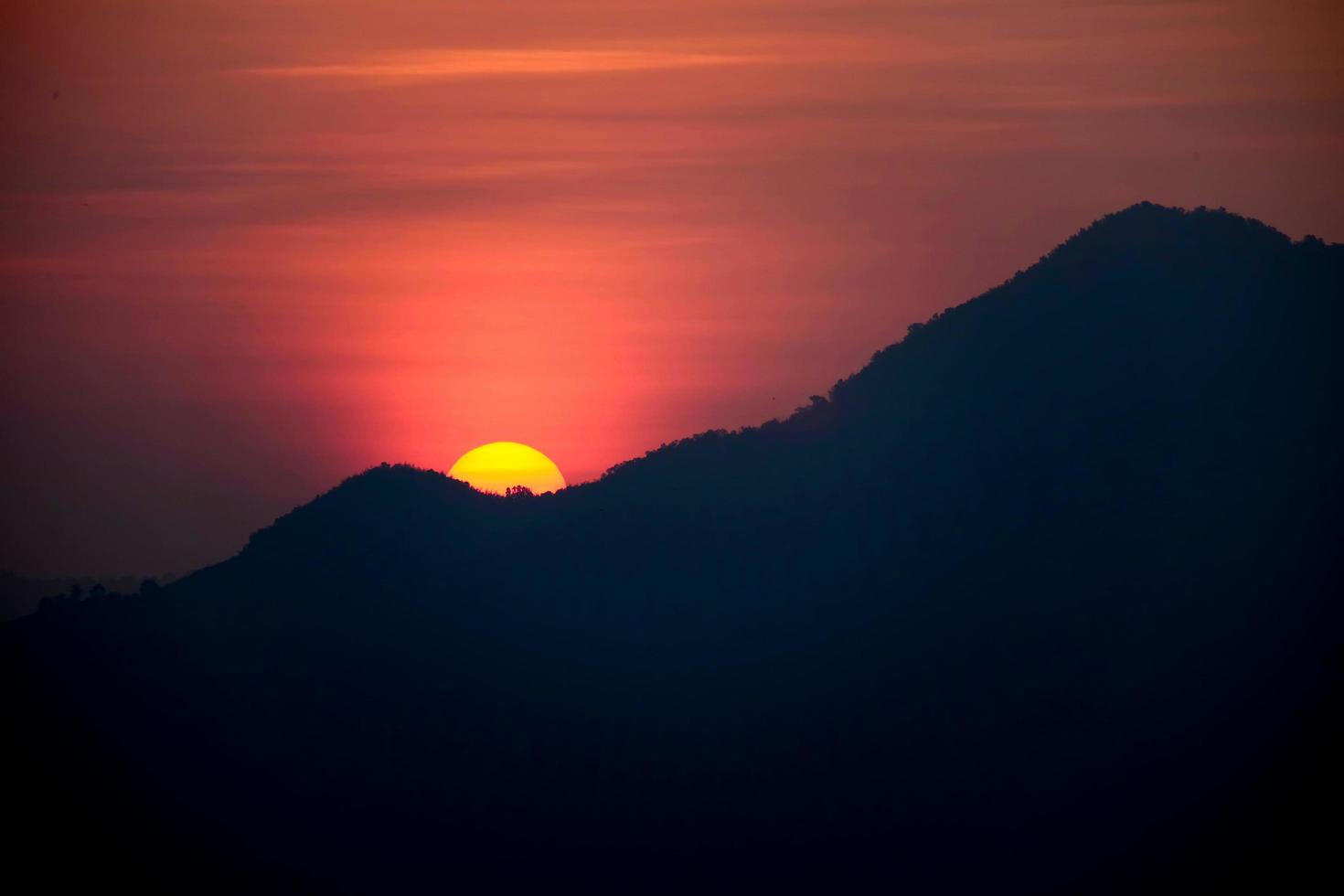 le soleil se lève derrière la montagne photo