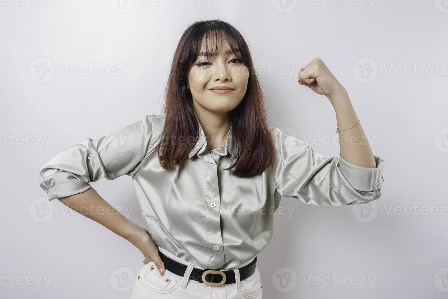 femme asiatique excitée portant une chemise vert sauge montrant un geste fort en levant les bras et les muscles en souriant fièrement photo