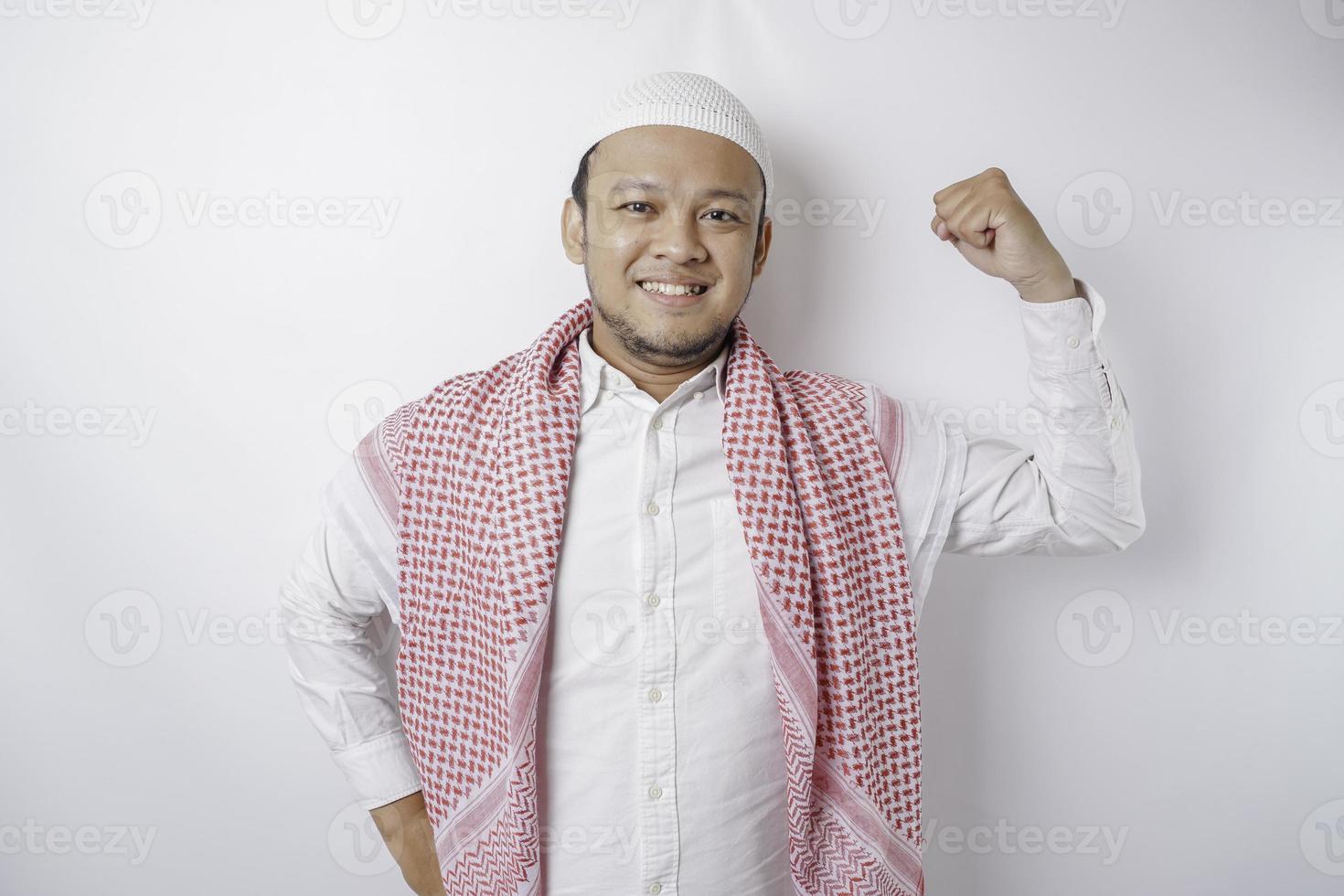 homme musulman asiatique excité montrant un geste fort en levant les bras et les muscles en souriant fièrement photo