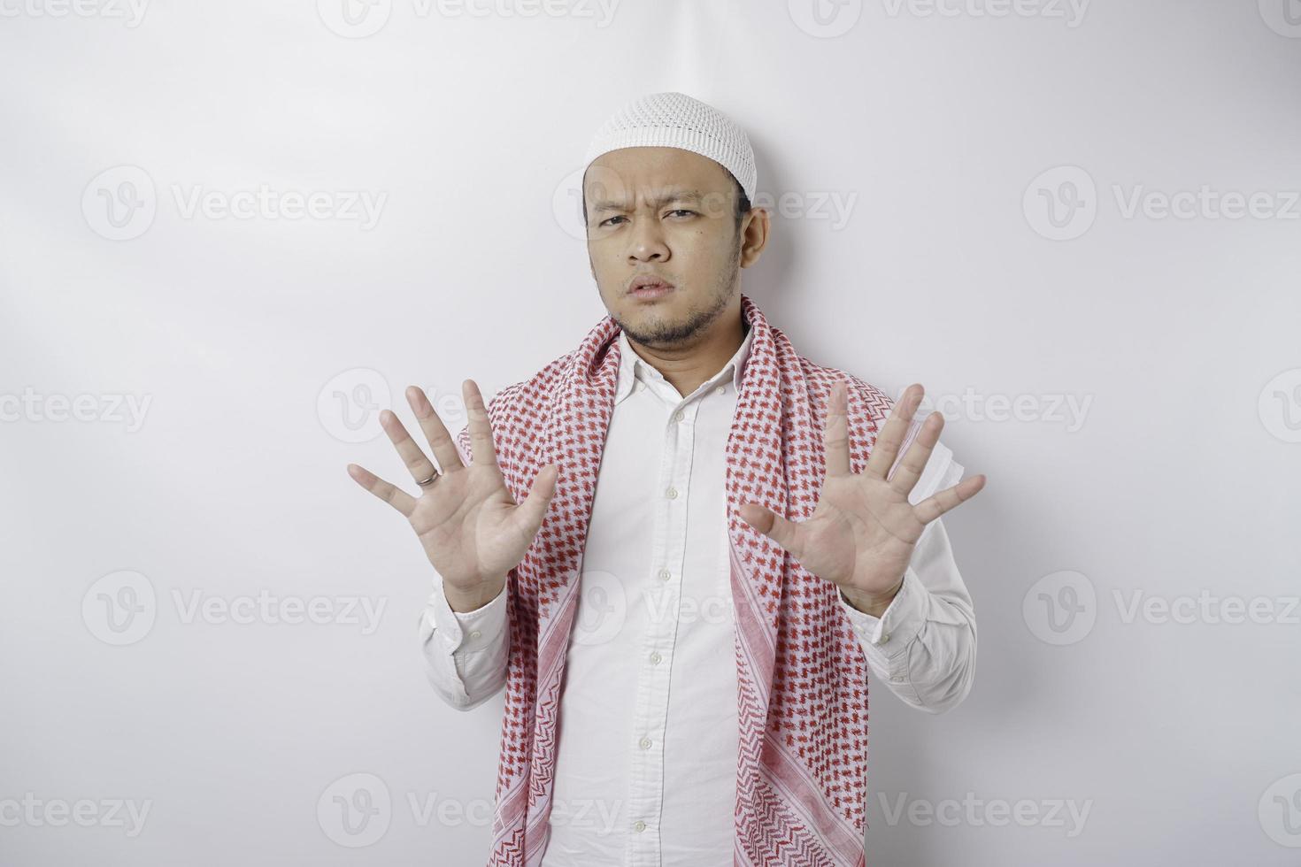 jeune homme musulman asiatique isolé sur fond blanc, a l'air déprimé, le visage couvert de doigts effrayés et nerveux. photo