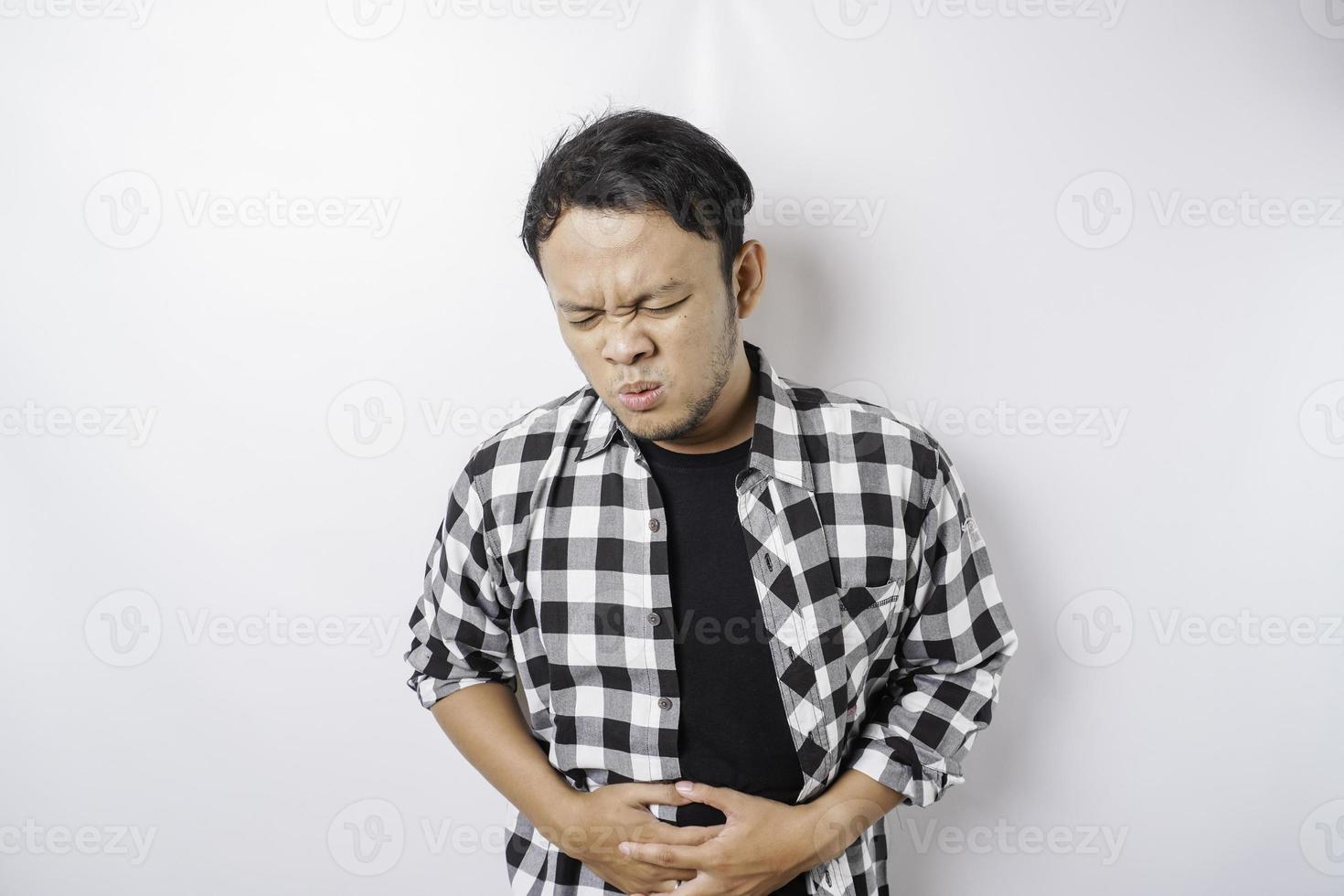 Photo d'un jeune homme malade malade malade tenir la main sur l'estomac souffre de douleur isolé sur fond blanc