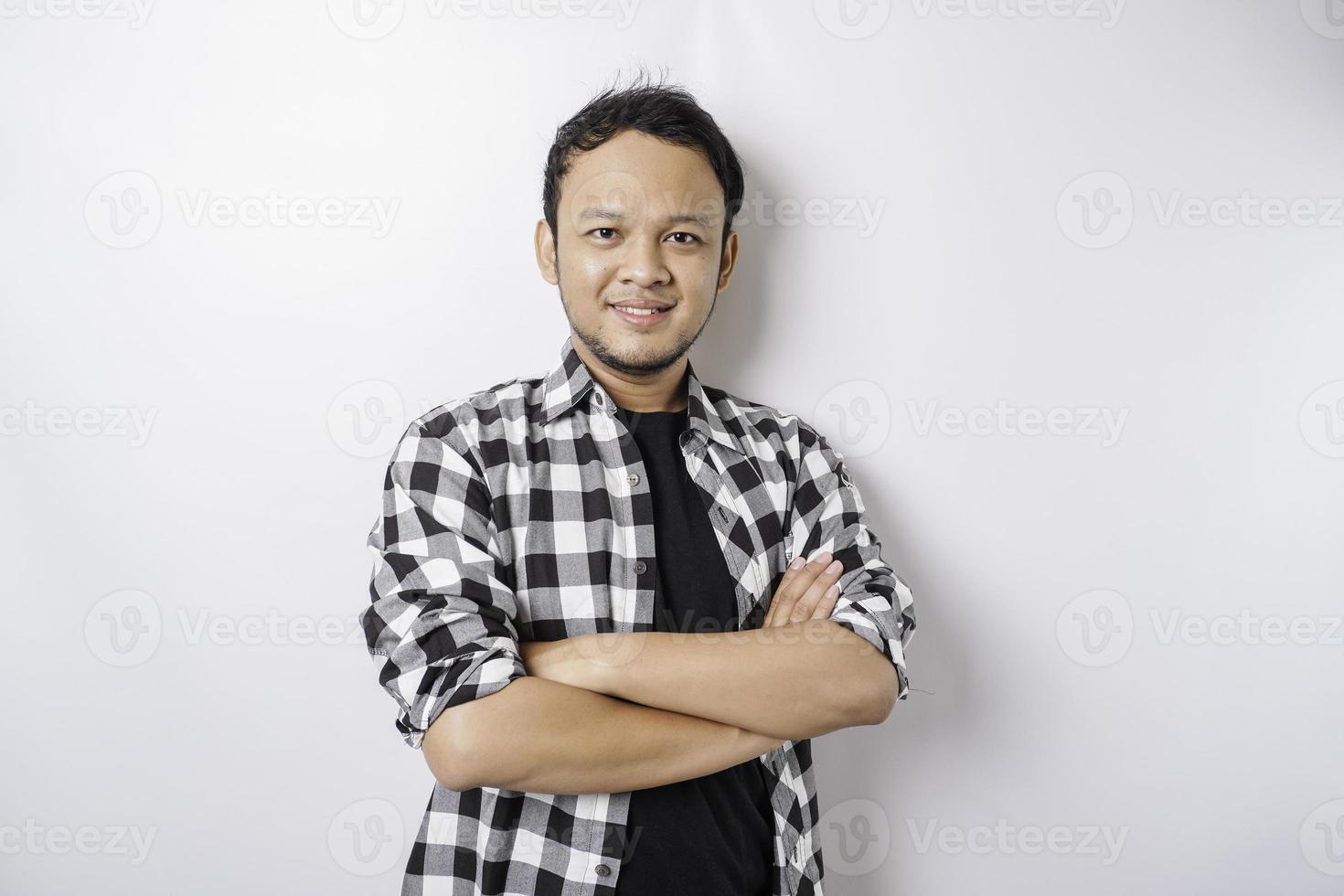 portrait d'un homme asiatique souriant confiant portant une chemise tartan debout avec les bras croisés et regardant la caméra isolée sur fond blanc photo