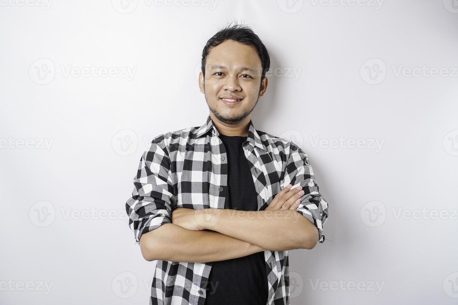 portrait d'un homme asiatique souriant confiant portant une chemise tartan debout avec les bras croisés et regardant la caméra isolée sur fond blanc photo