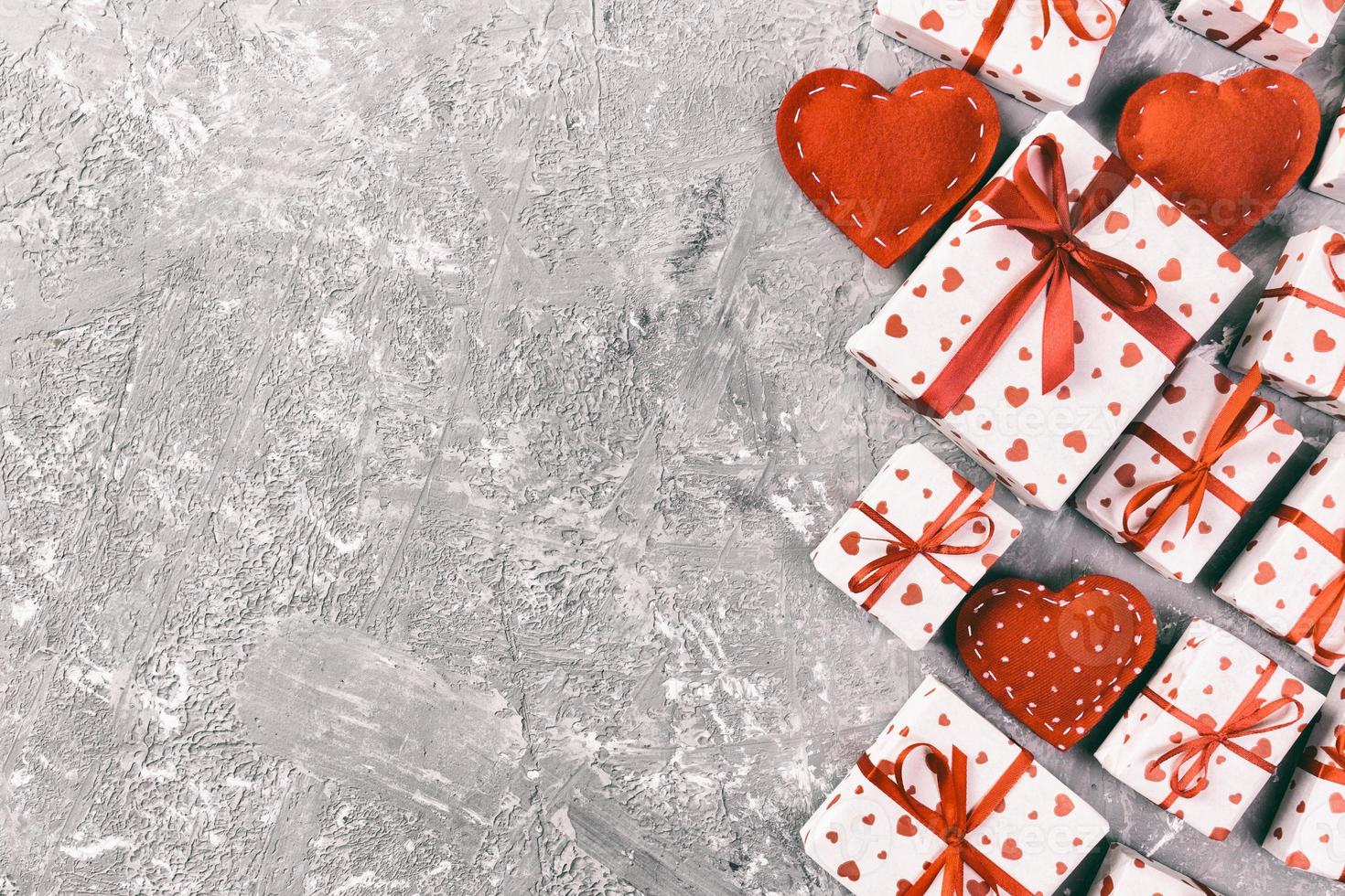 saint valentin ou autre cadeau de vacances fait à la main en papier avec des coeurs rouges et une boîte de cadeaux dans un emballage de vacances. boîte cadeau présente sur la vue de dessus de table en ciment gris avec espace de copie, espace vide pour la conception photo