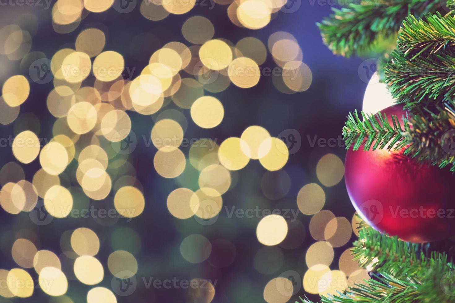 gros plan d'une variété colorée de boules suspendue à un arbre de noël décoré sur des lumières floues avec un arbre décoré, un arrière-plan étincelant et bokeh. copiez l'espace pour votre texte. décoration d'arbre de Noël photo