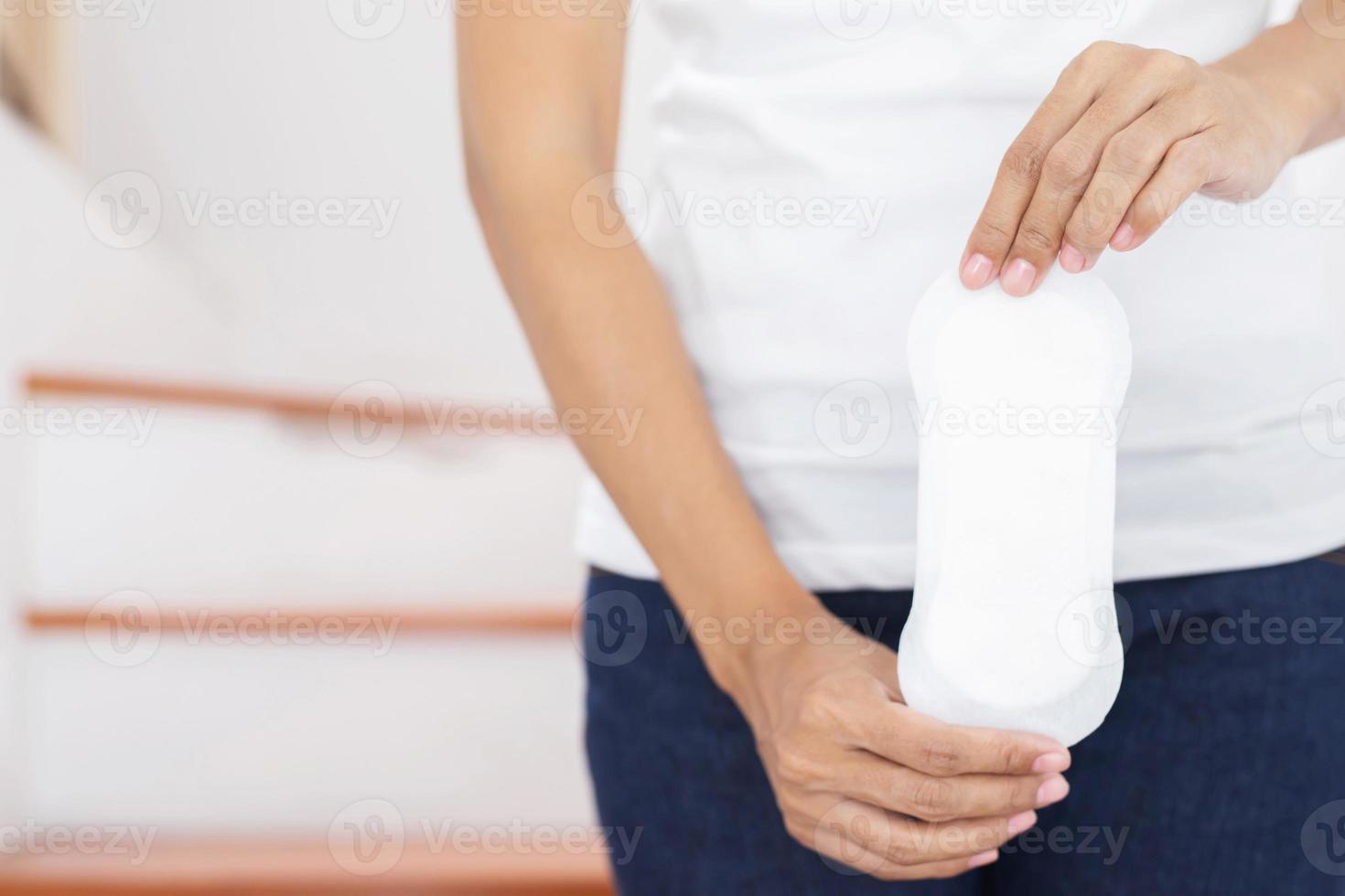 hygiène féminine. gros plan jeune femme tenant un tampon de serviette hygiénique mince de période propre. rapporte l'utilisation quotidienne de la période menstruelle tous les mois. produit intime féminin. notion de soins de santé. photo