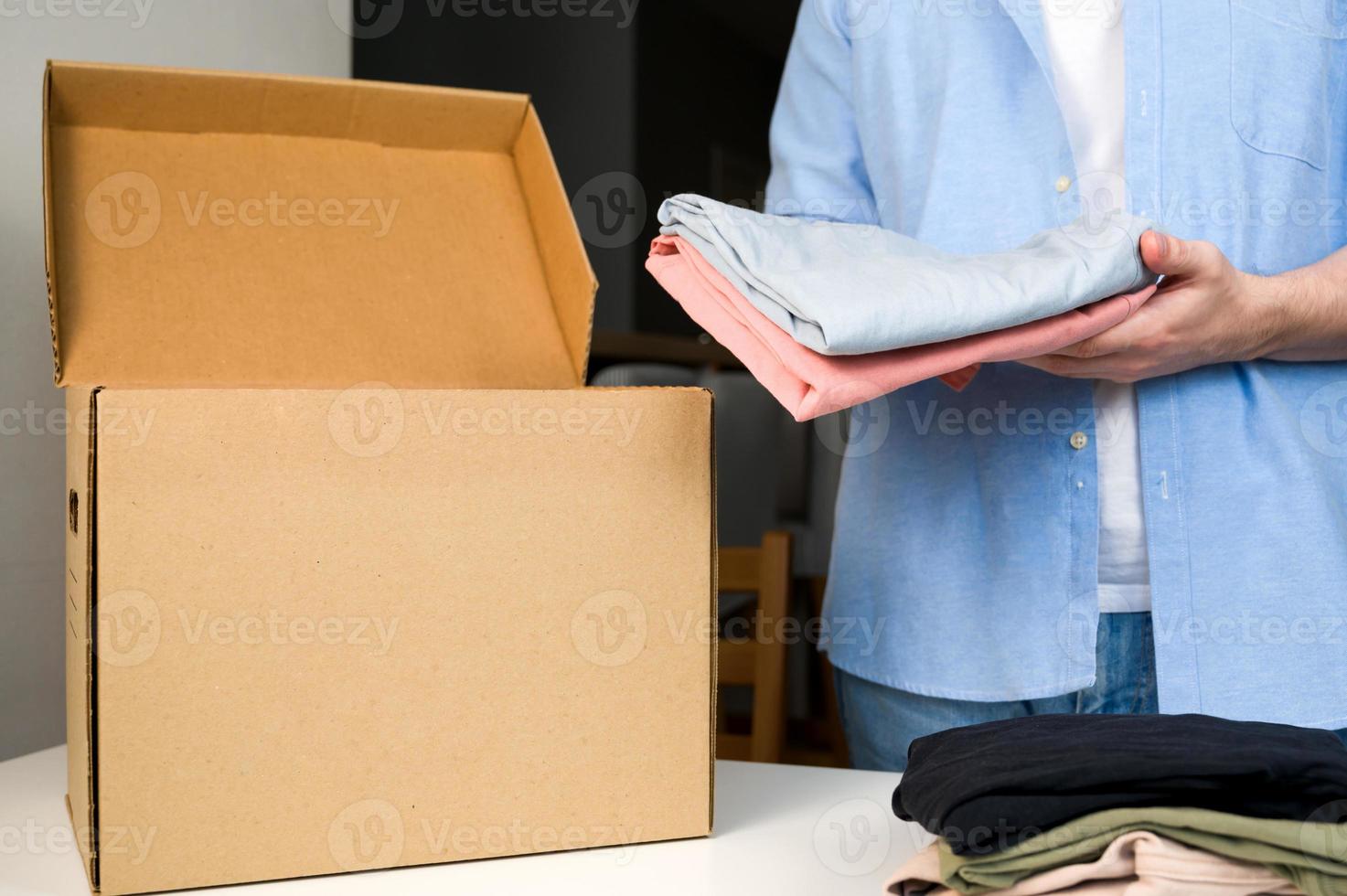 gros plan d'un homme méconnaissable mettant des vêtements dans une boîte. concept de recyclage ou de dons. durabilité et charité photo