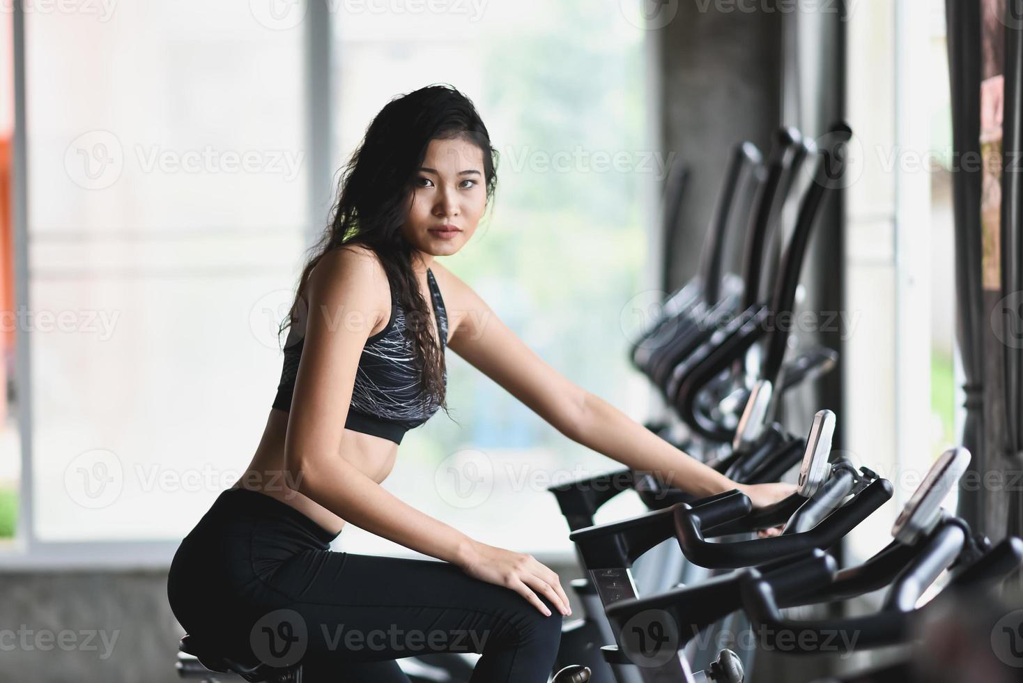 sportive asiatique faisant de l'exercice sur un vélo dans la salle de gym, la détermination à perdre du poids cardio, la rend en bonne santé. vélo d'exercice concept de sport fitness femme. photo