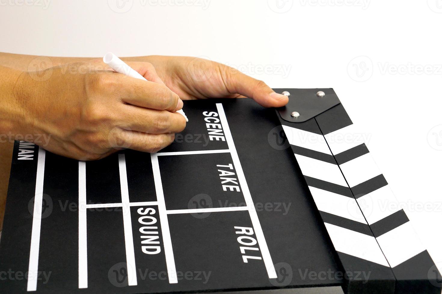 la main tient un panneau de clapet ou une ardoise de film de couleur noire et un stylo marqueur. concept de l'industrie du cinéma. photo