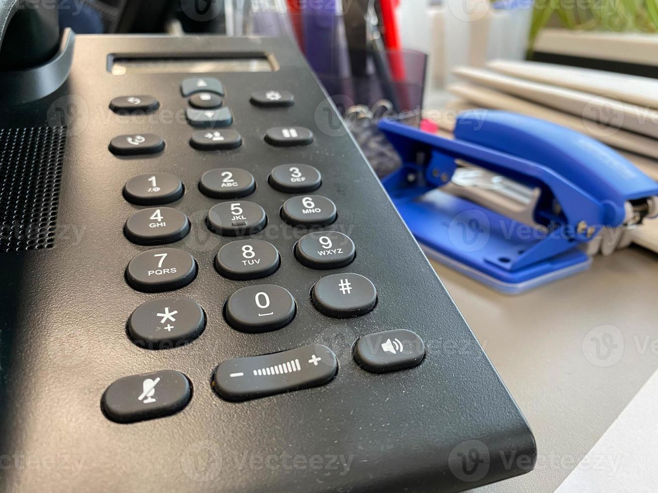 téléphone filaire fixe de bureau en plastique noir avec un combiné et des boutons pour résoudre les problèmes commerciaux et passer des appels pour les négociations photo