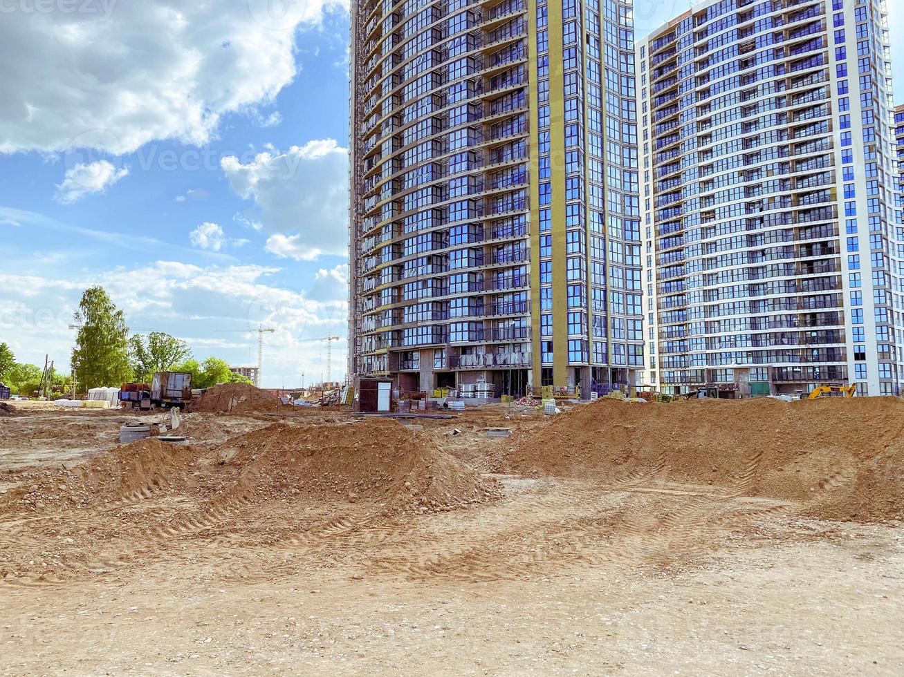 construction d'immeubles de grande hauteur. construction de maisons de verre. nouveau quartier du centre-ville. trois maisons de verre avec fenêtres panoramiques. construire du sable à côté des maisons photo