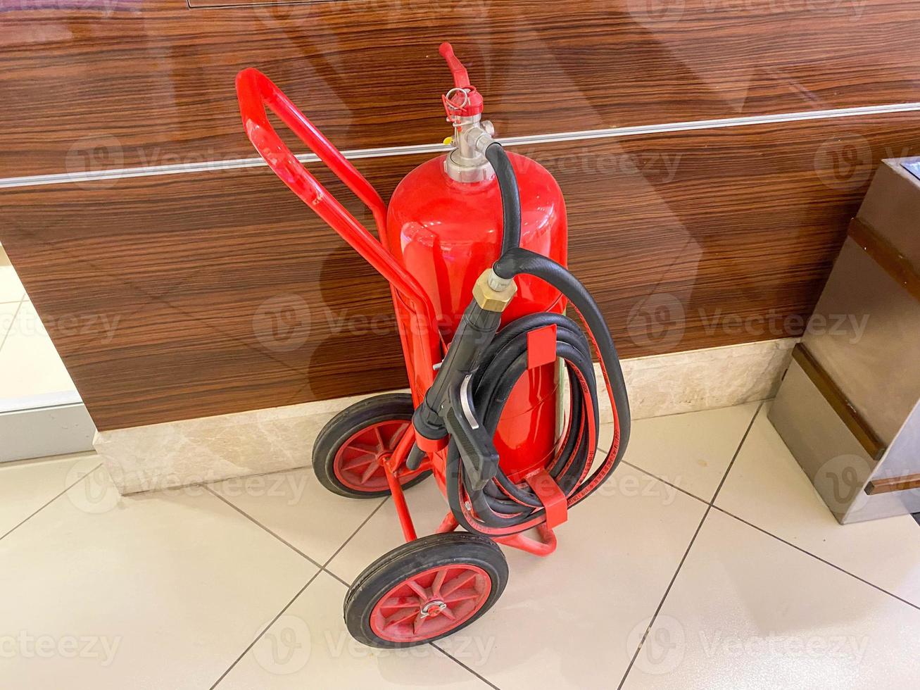 un grand extincteur mobile en fer rouge avec un tuyau sur roues pour éteindre les incendies photo