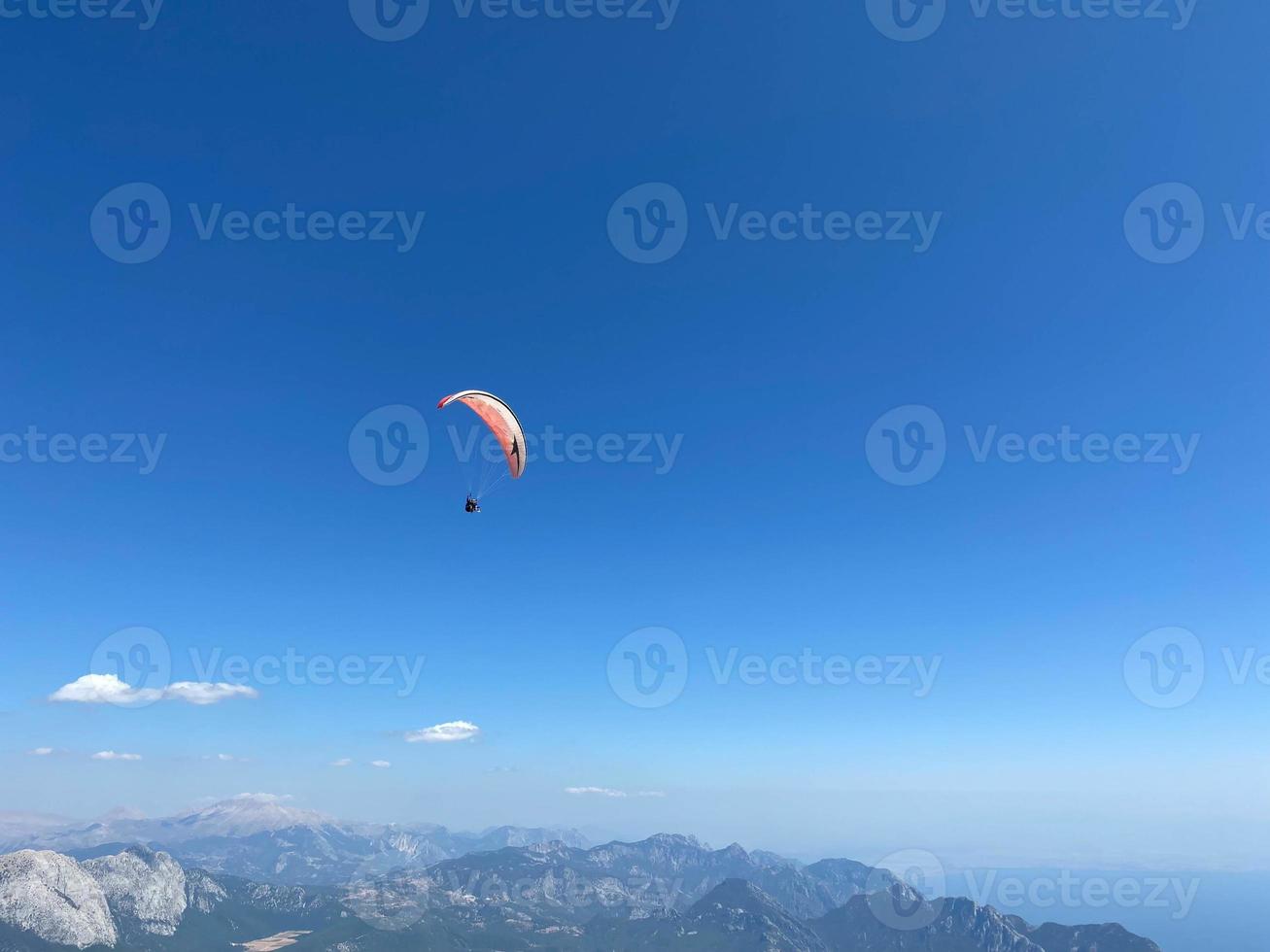 le parachutiste volant haut dans le ciel bleu sur un parachute coloré photo