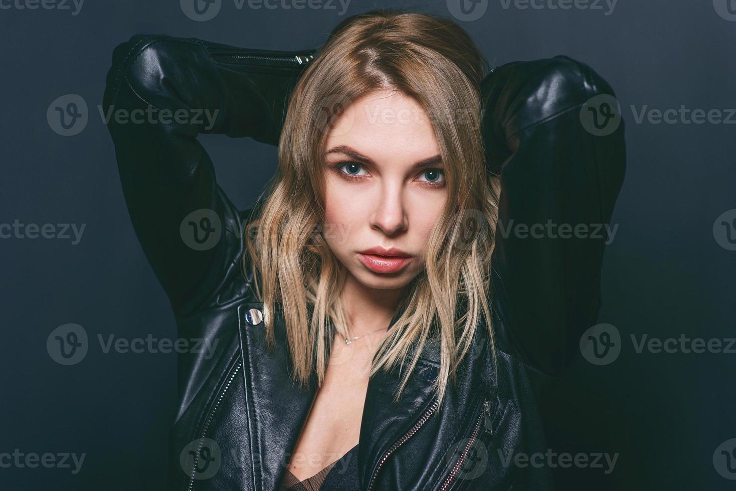 portrait de jeune femme blonde élégante et séduisante en robe de soie et veste noire sur fond sombre photo