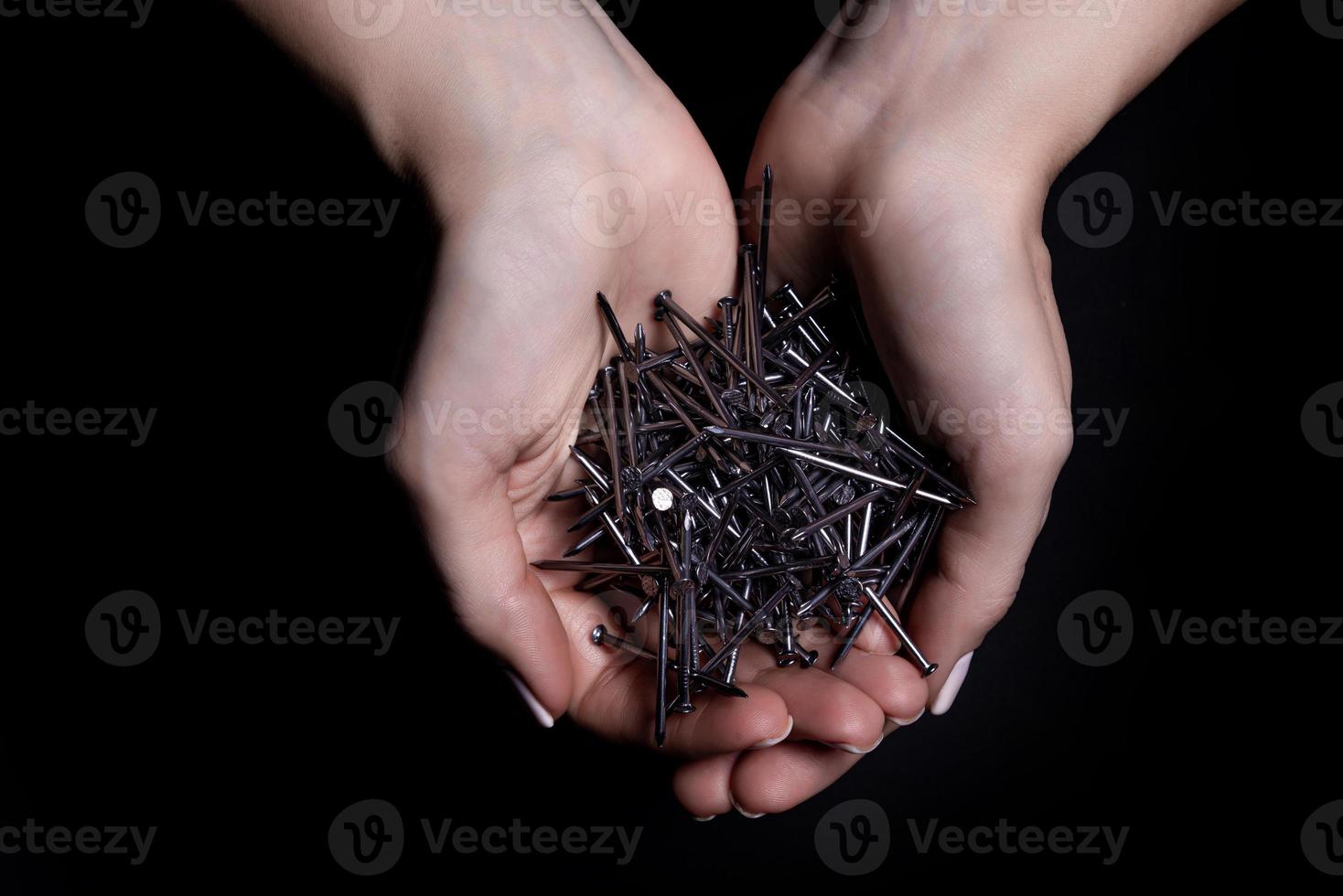 mains de femme tenant des vis et des chevilles dans les paumes. isolé sur noir. les mains des femmes tiennent les vis les clous les rondelles les écrous sur un fond noir photo