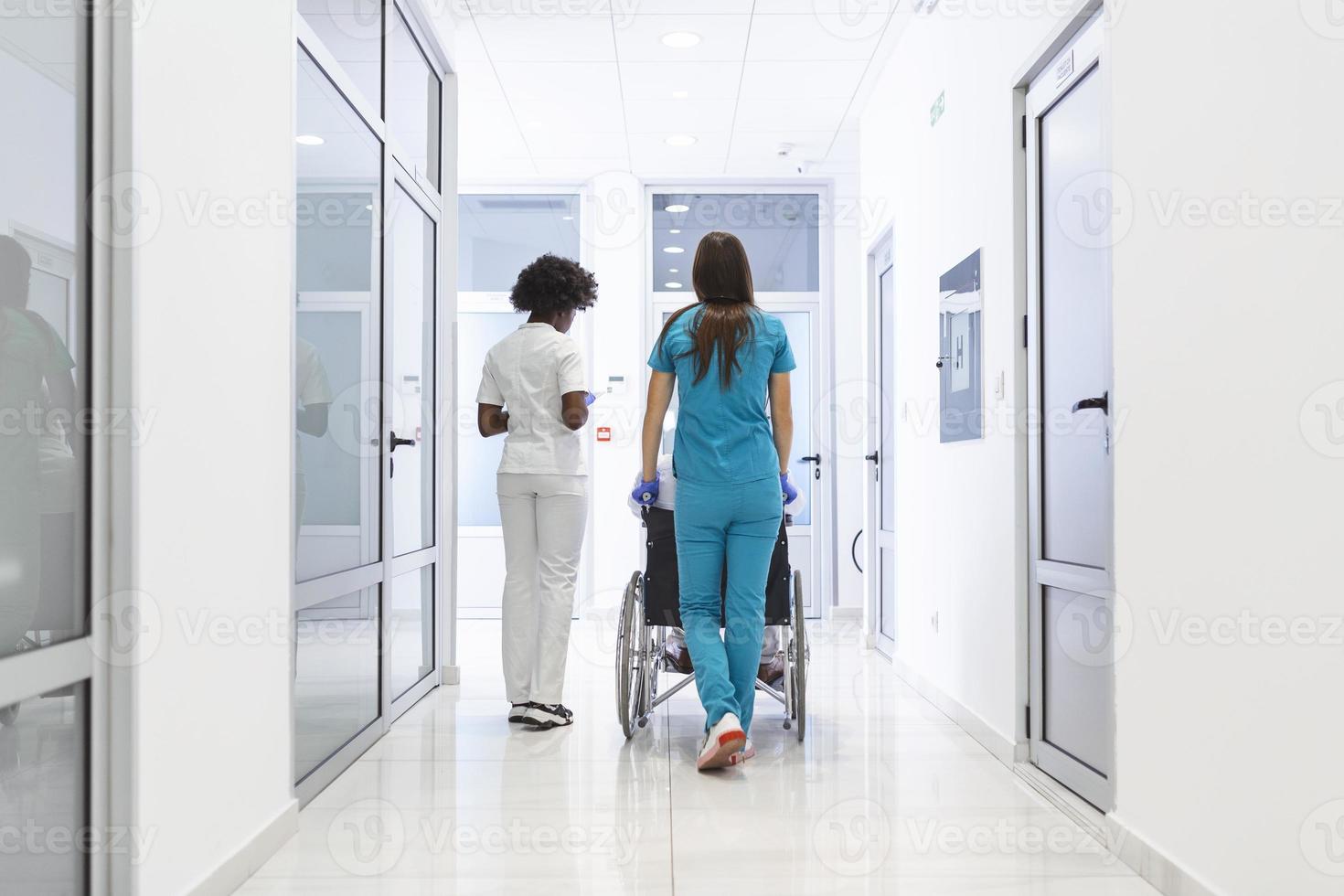 patient en fauteuil roulant avec une femme médecin afro-américaine professionnelle et une infirmière spécialisée dans le couloir du centre de récupération de l'hôpital photo