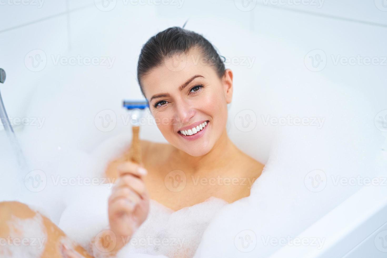 belle jeune femme brune prenant un bain dans la baignoire photo