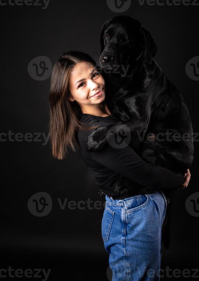 une fille tient un chien labrador retriever dans ses bras. photo