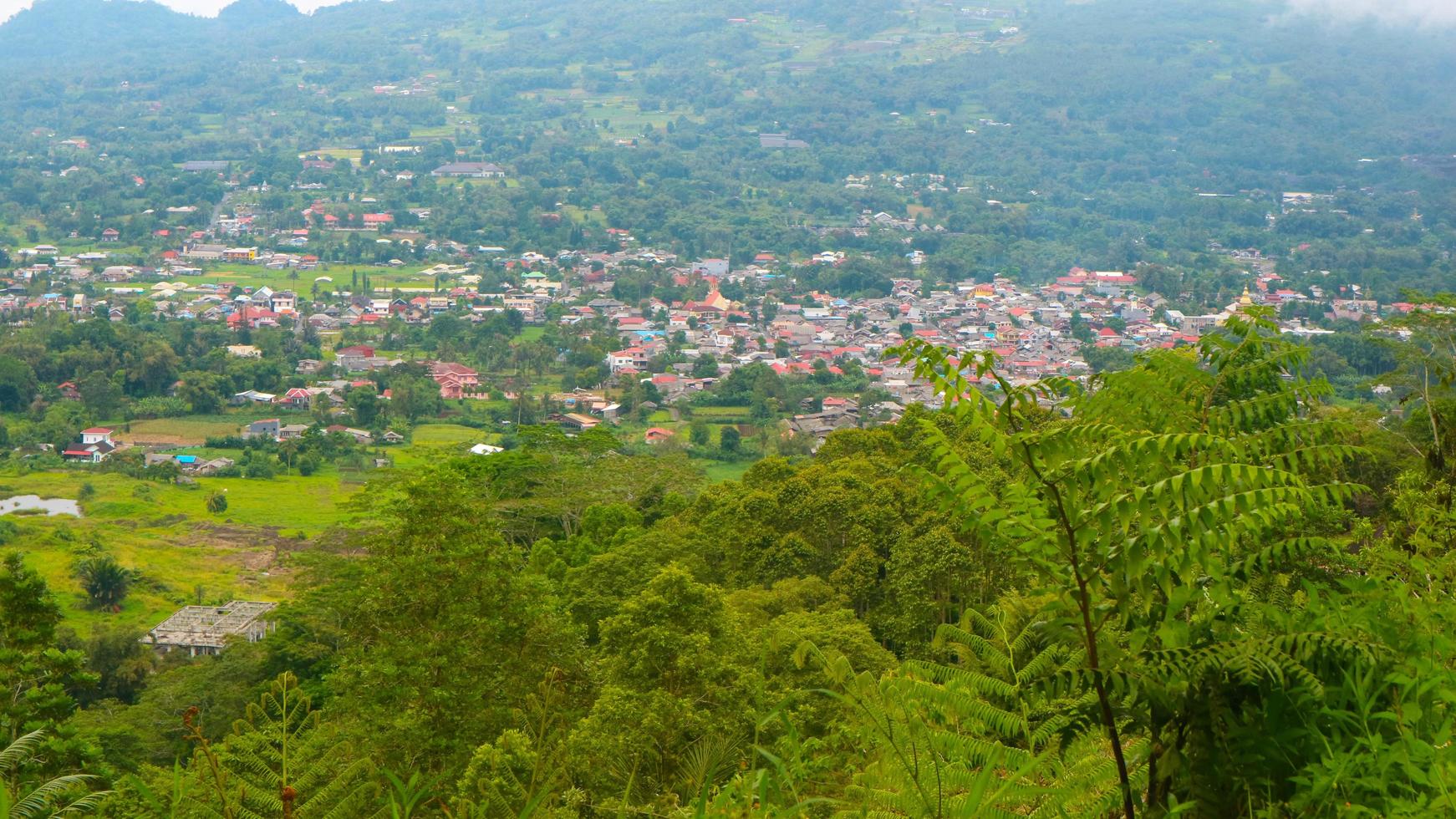 la vue sur le ciel nuageux, les arbres, les montagnes et les maisons a été photographiée au-dessus de la colline photo