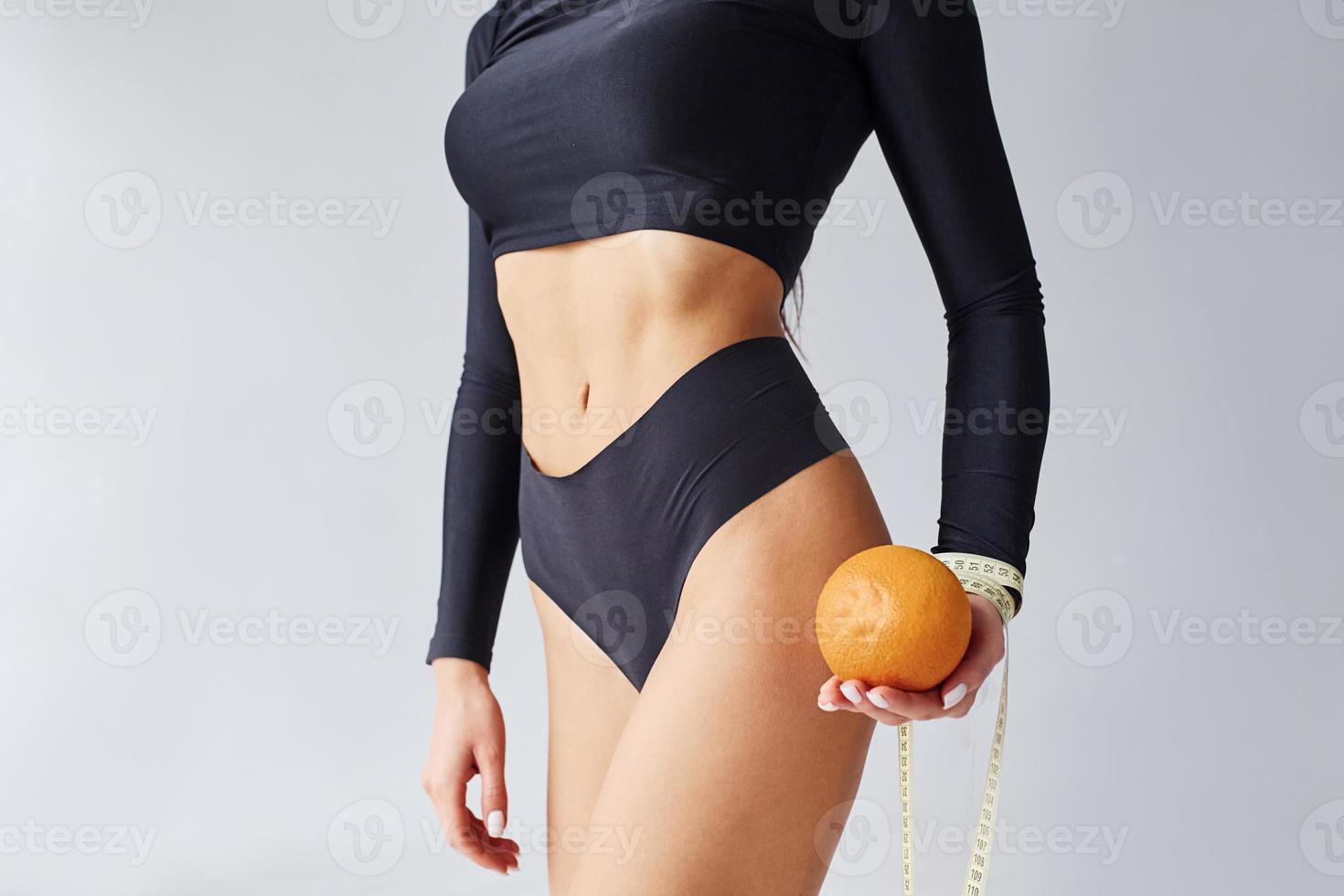 vue rapprochée d'une femme sportive avec orange et ruban à mesurer dans le studio photo