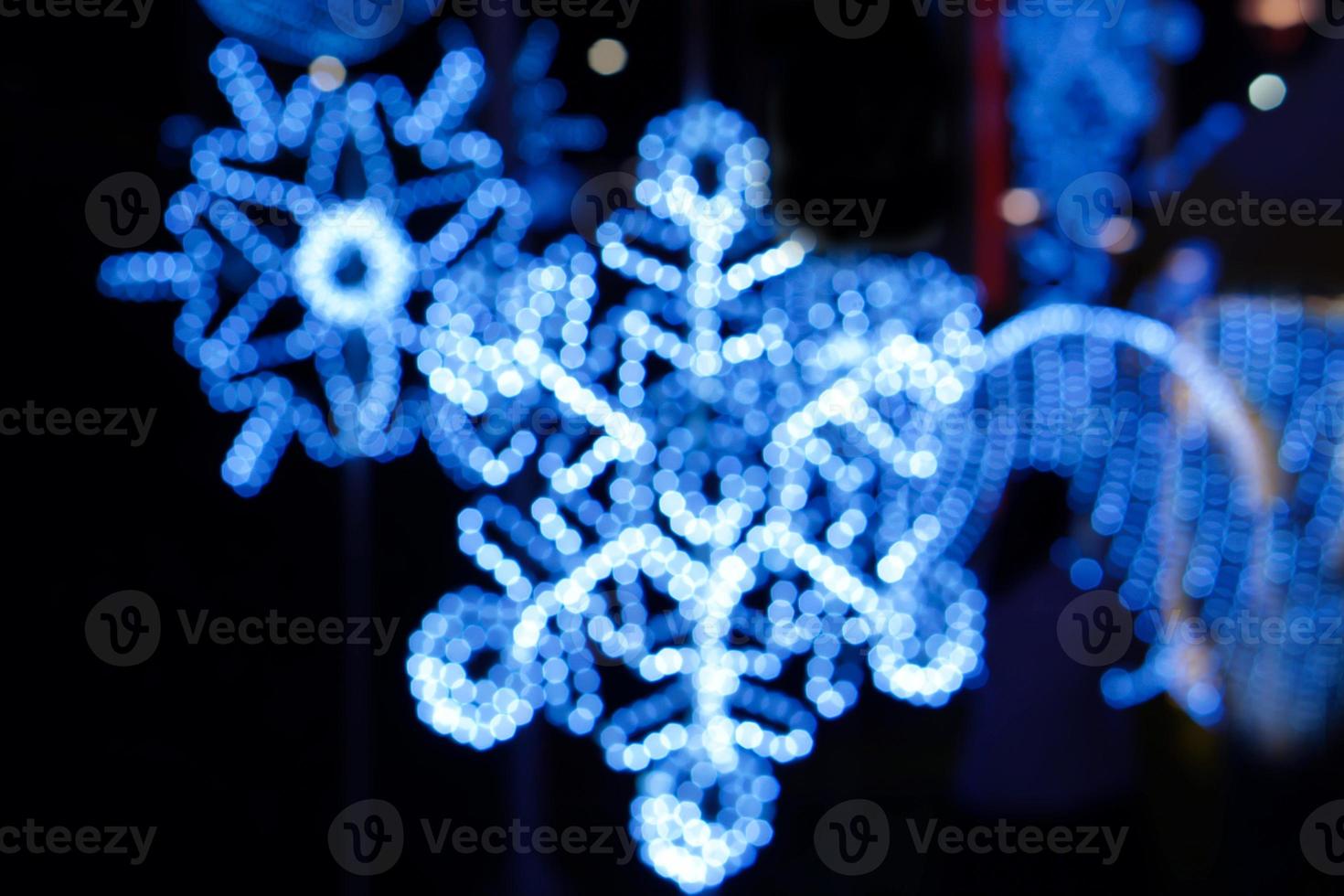 flou et bokeh décoré led d'éclairage bleu de noël en forme de flocon de neige la nuit et arrière-plan flou. photo