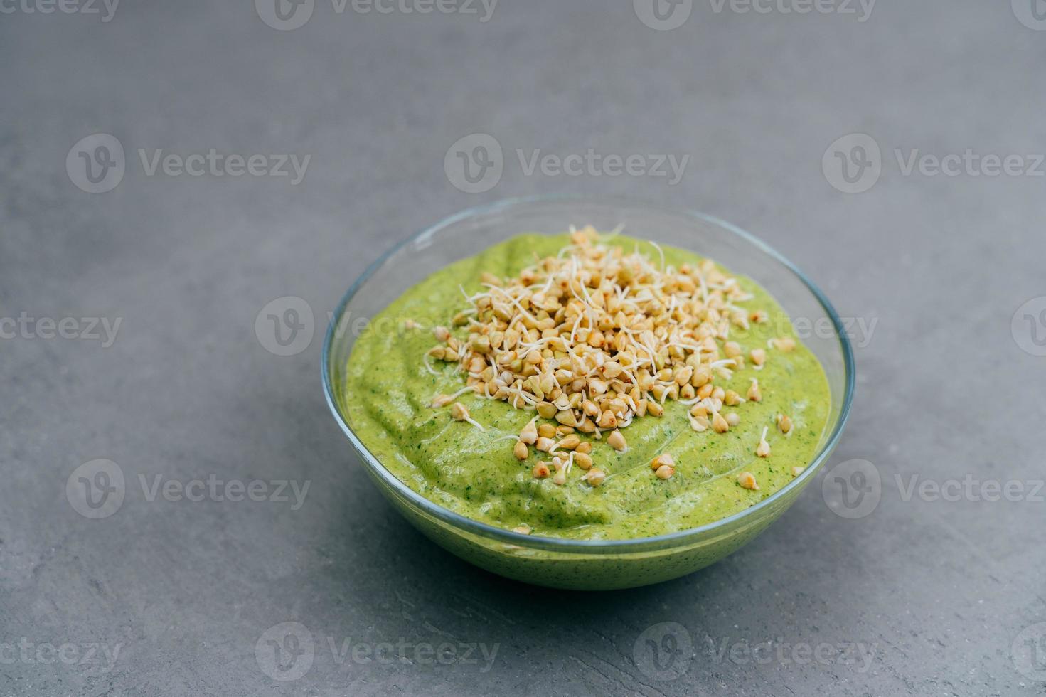 bol de smoothie vert fait d'épinards avec des pousses de sarrasin sur fond gris. nourriture végétalienne. concept de saine alimentation et de nutrition photo