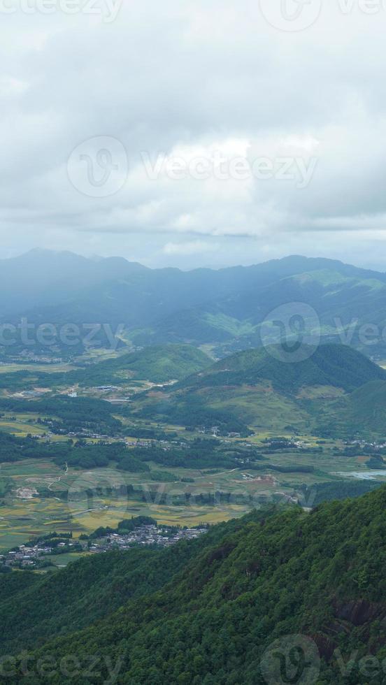 la vue sur le champ de riz jaune de récolte situé dans la vallée parmi les montagnes avec le ciel nuageux en arrière-plan photo