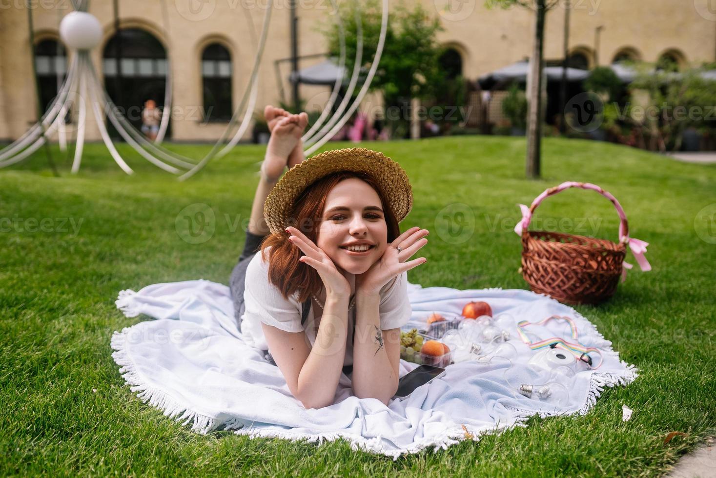 heureuse jeune femme allongée sur une couverture sur la pelouse du parc photo