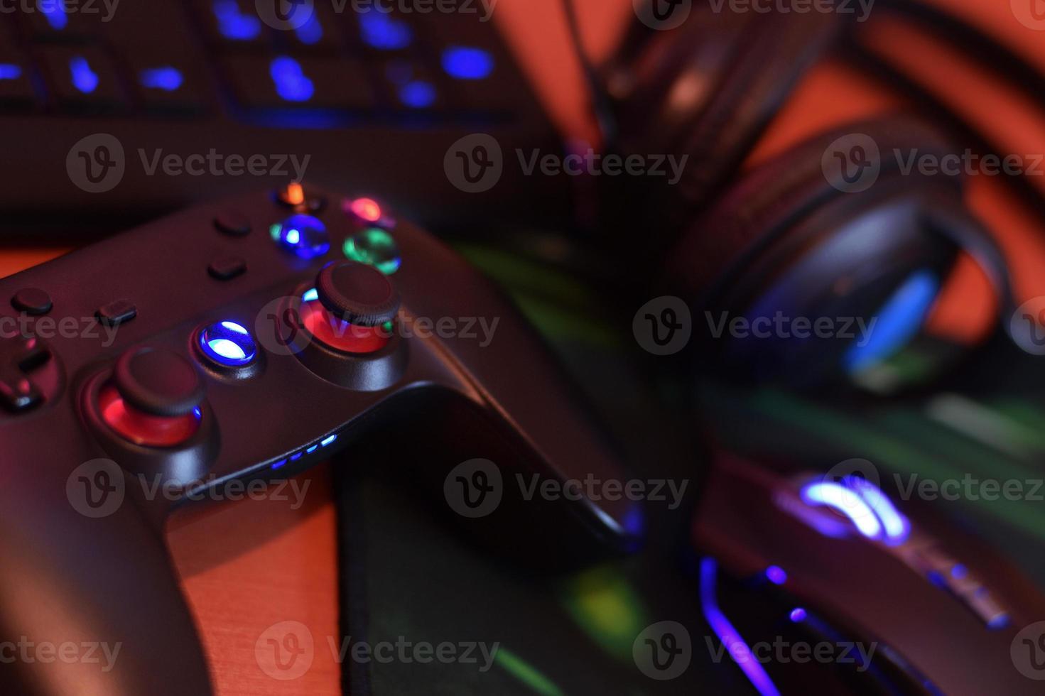 une manette de jeu moderne et une souris de jeu se trouvent avec un clavier et un casque sur la table dans une scène de salle de jeux sombre. électronique moderne pour les compétitions professionnelles de cybersport photo