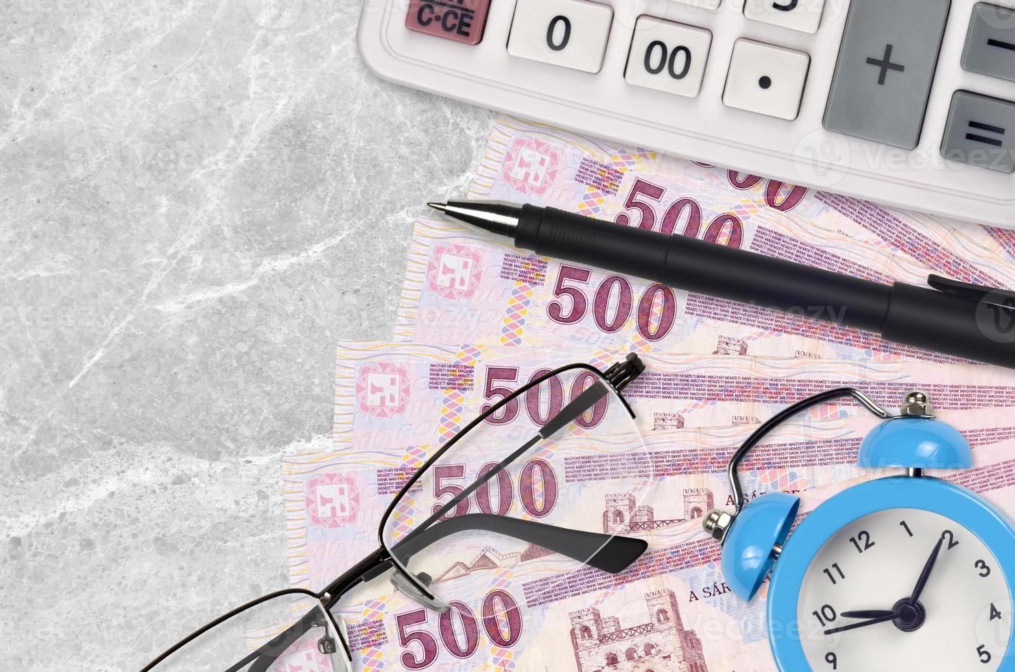 500 factures de forint hongrois et calculatrice avec lunettes et stylo. prêt commercial ou concept de saison de paiement des impôts. le temps de payer les impôts photo