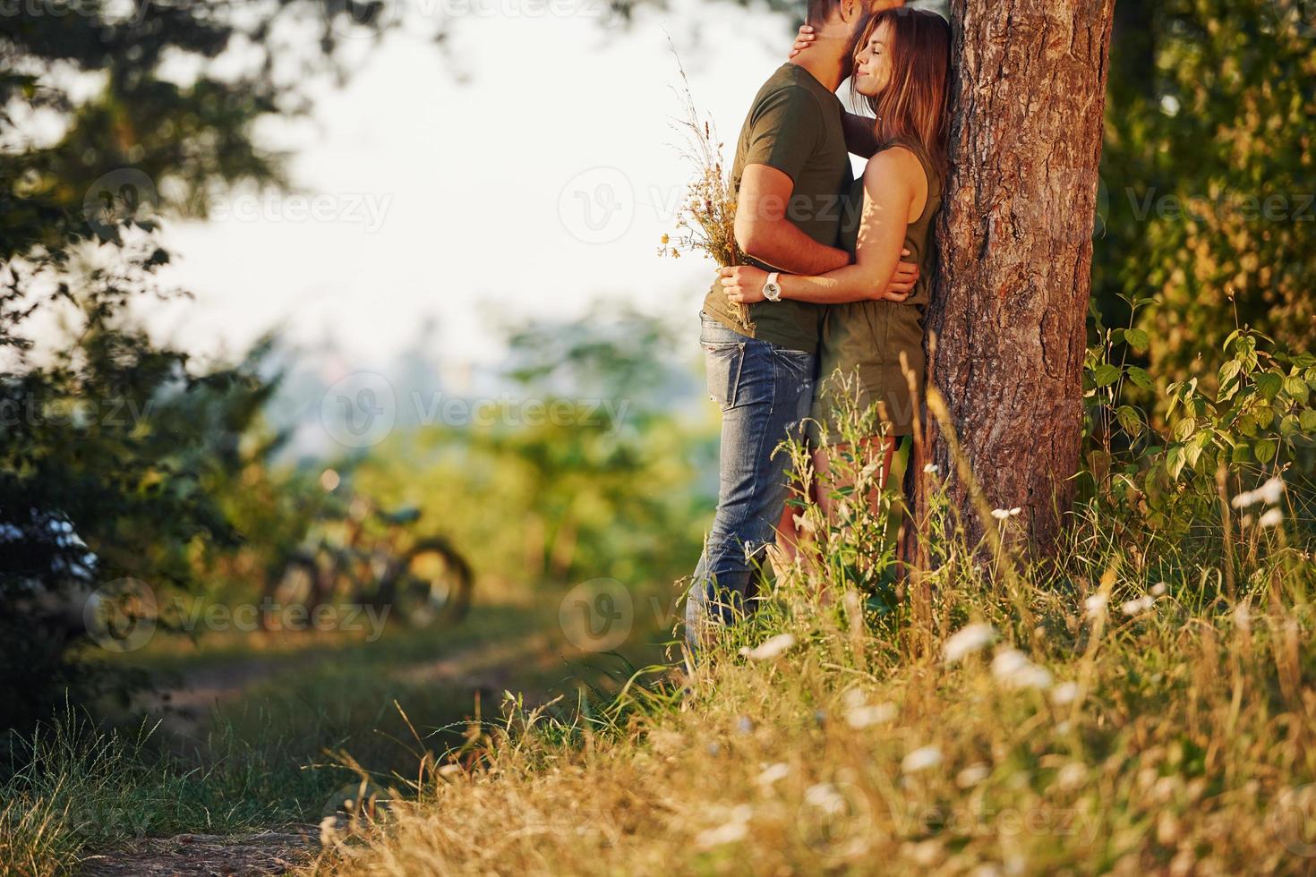 appuyé sur l'arbre. beau jeune couple passe un bon moment dans la forêt pendant la journée photo