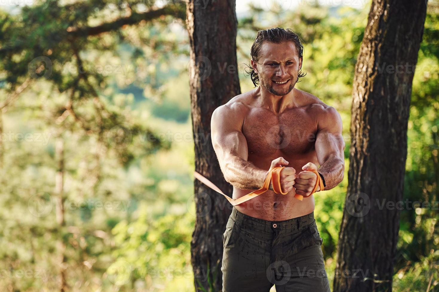 faire de l'exercice. bel homme torse nu avec un type de corps musclé est dans la forêt pendant la journée photo