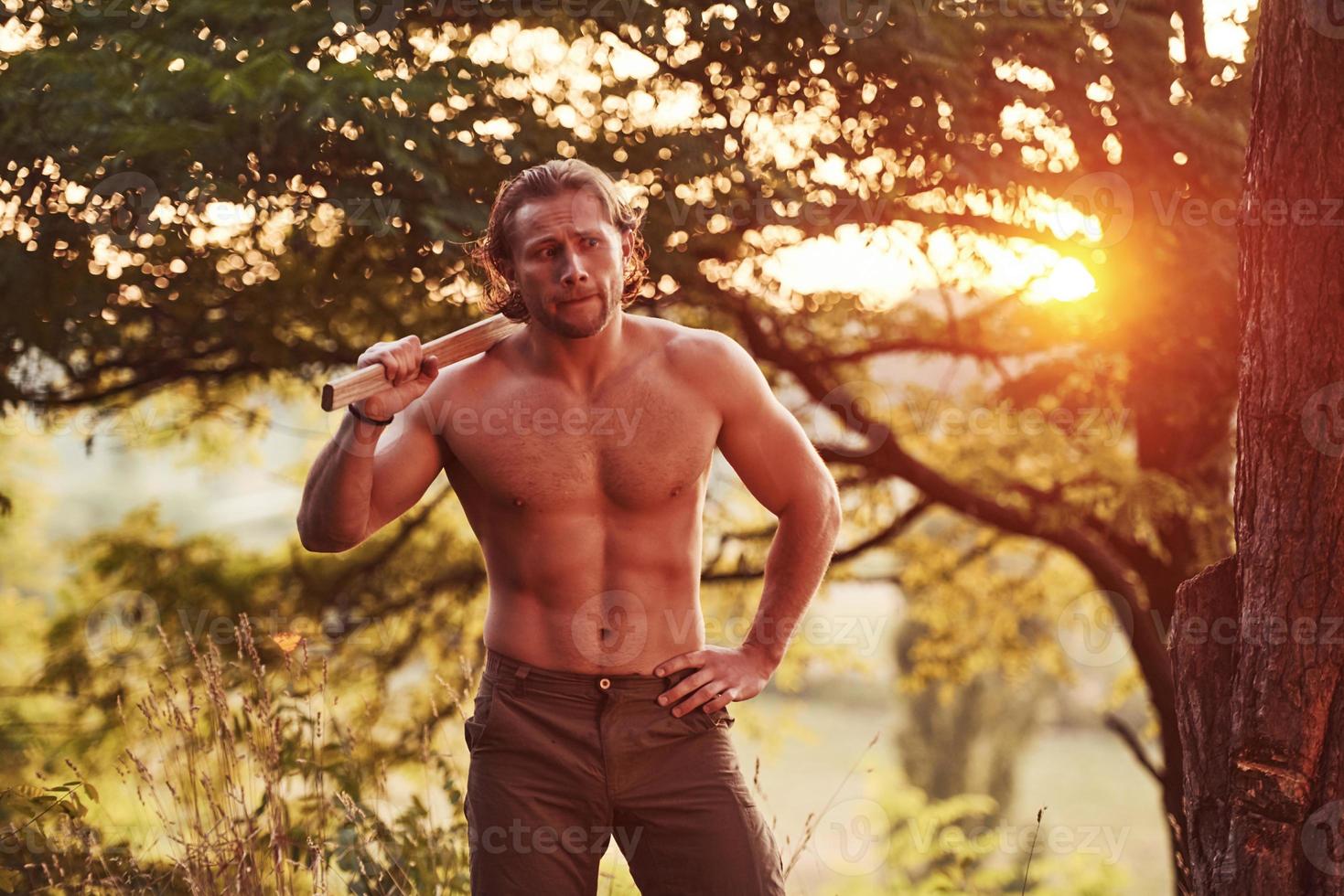 dans les bois. bel homme torse nu avec un type de corps musclé est dans la forêt pendant la journée photo