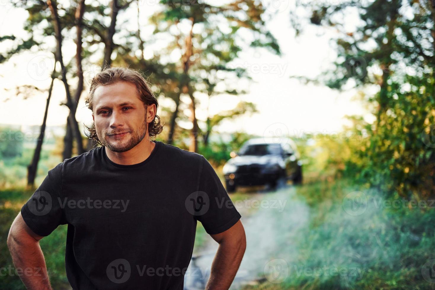 portrait d'homme qui se tient dans la forêt et regarde la nature. voiture garée derrière photo