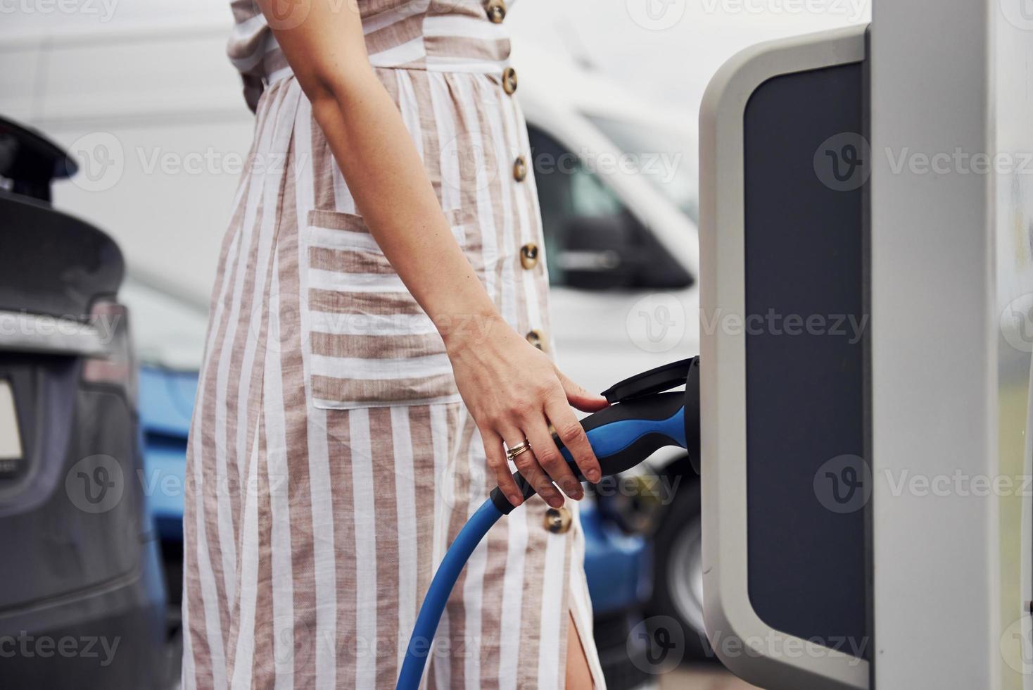 femme sur la station de charge des voitures électriques pendant la journée. véhicule neuf photo