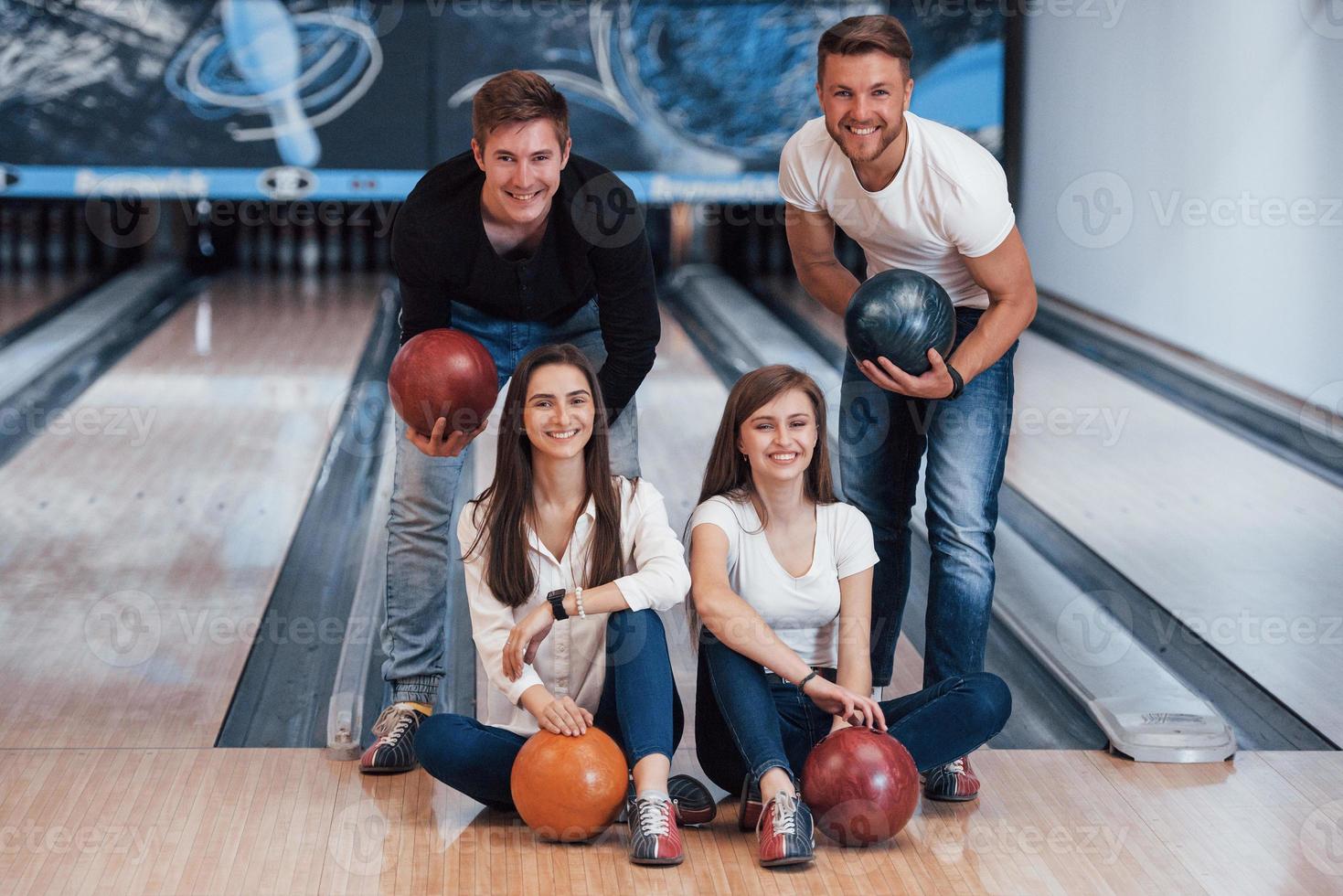 joli portrait. de jeunes amis joyeux s'amusent au club de bowling le week-end photo