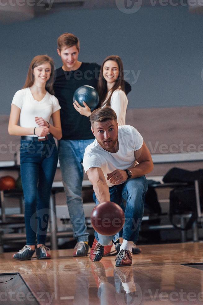 photographie verticale. de jeunes amis joyeux s'amusent au club de bowling le week-end photo