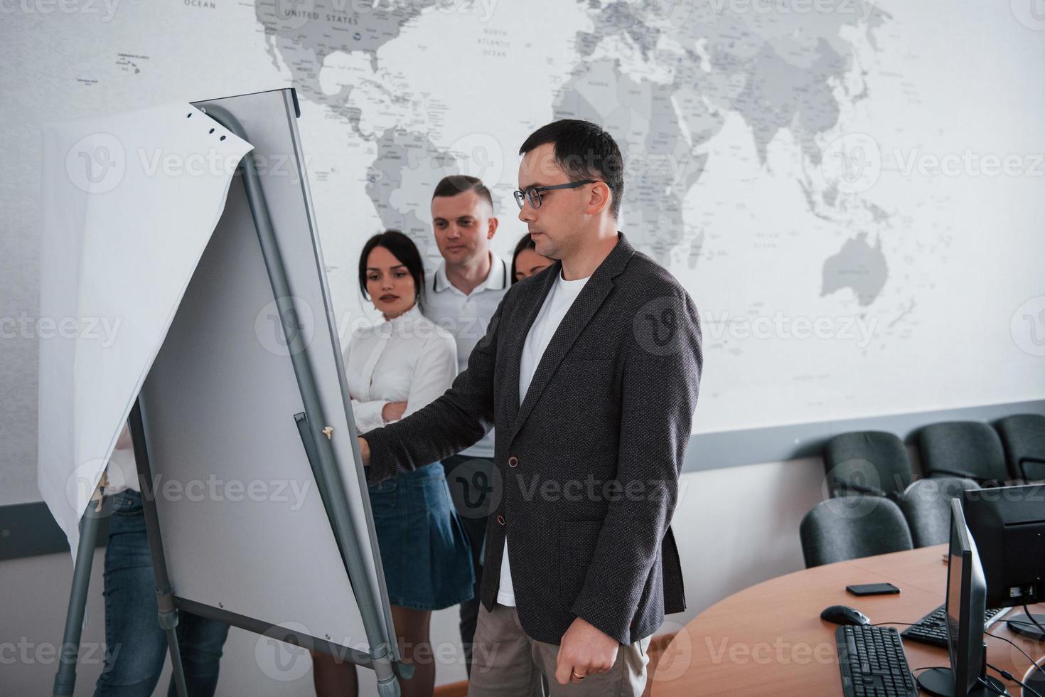 debout près du tableau blanc. gens d'affaires et gestionnaire travaillant sur leur nouveau projet en classe photo