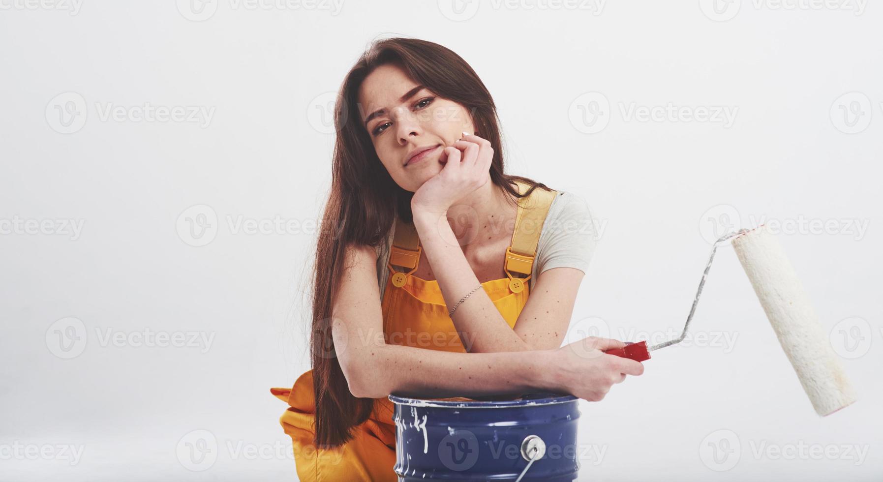 travail industriel. femme brune en uniforme jaune est assise sur fond blanc dans le studio photo