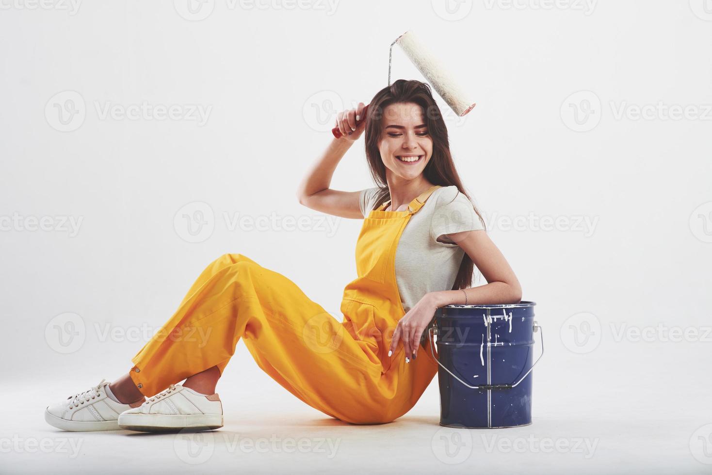 rendre facile. femme brune en uniforme jaune est assise sur fond blanc dans le studio photo