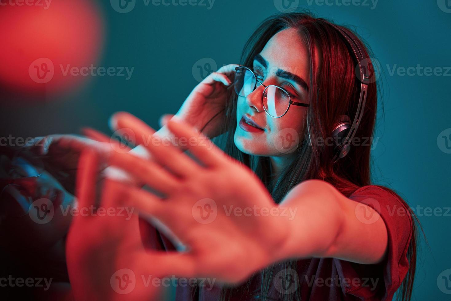 comme DJ à la fête. studio tourné à l'intérieur avec une lumière au néon. portrait de belle jeune fille photo