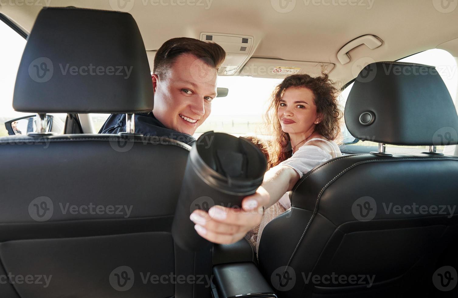 la femme partage le café. de belles personnes sont dans la voiture moderne le week-end photo