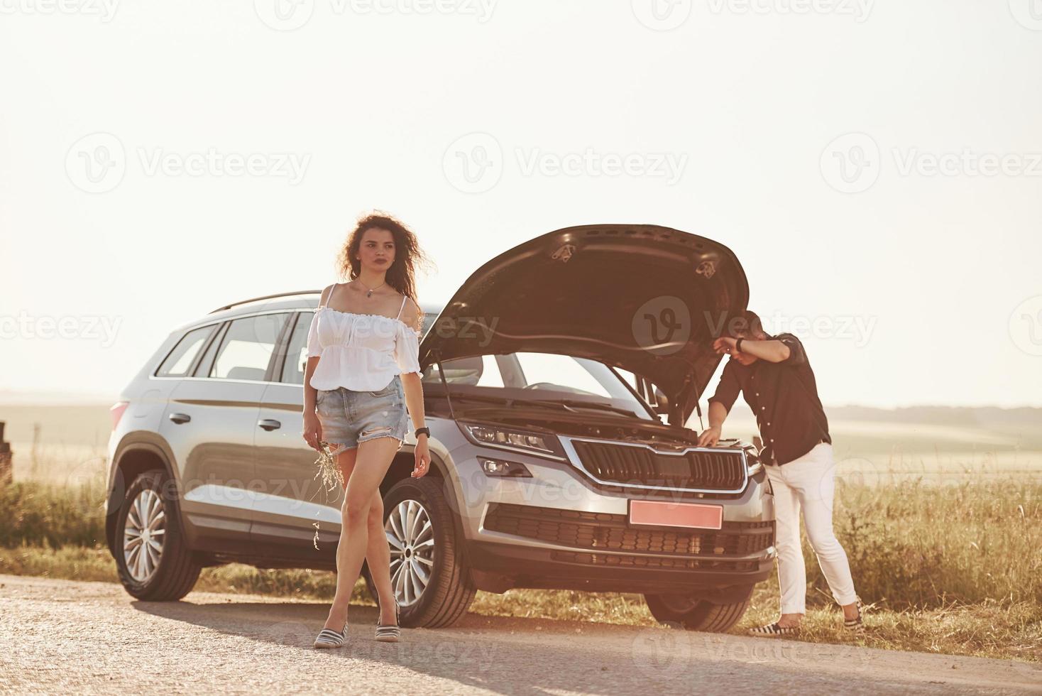 cela prendra du temps. l'homme répare la voiture d'une fille aux cheveux bouclés. assistance mécanique photo