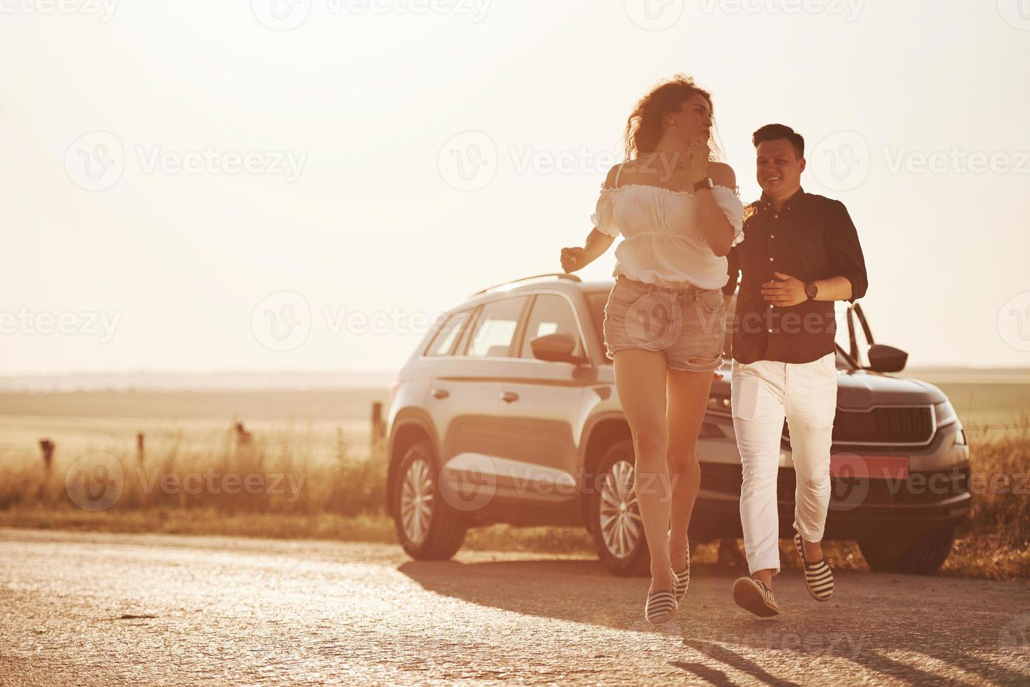 mouvement actif. beau couple près de leur nouvelle voiture moderne le week-end photo