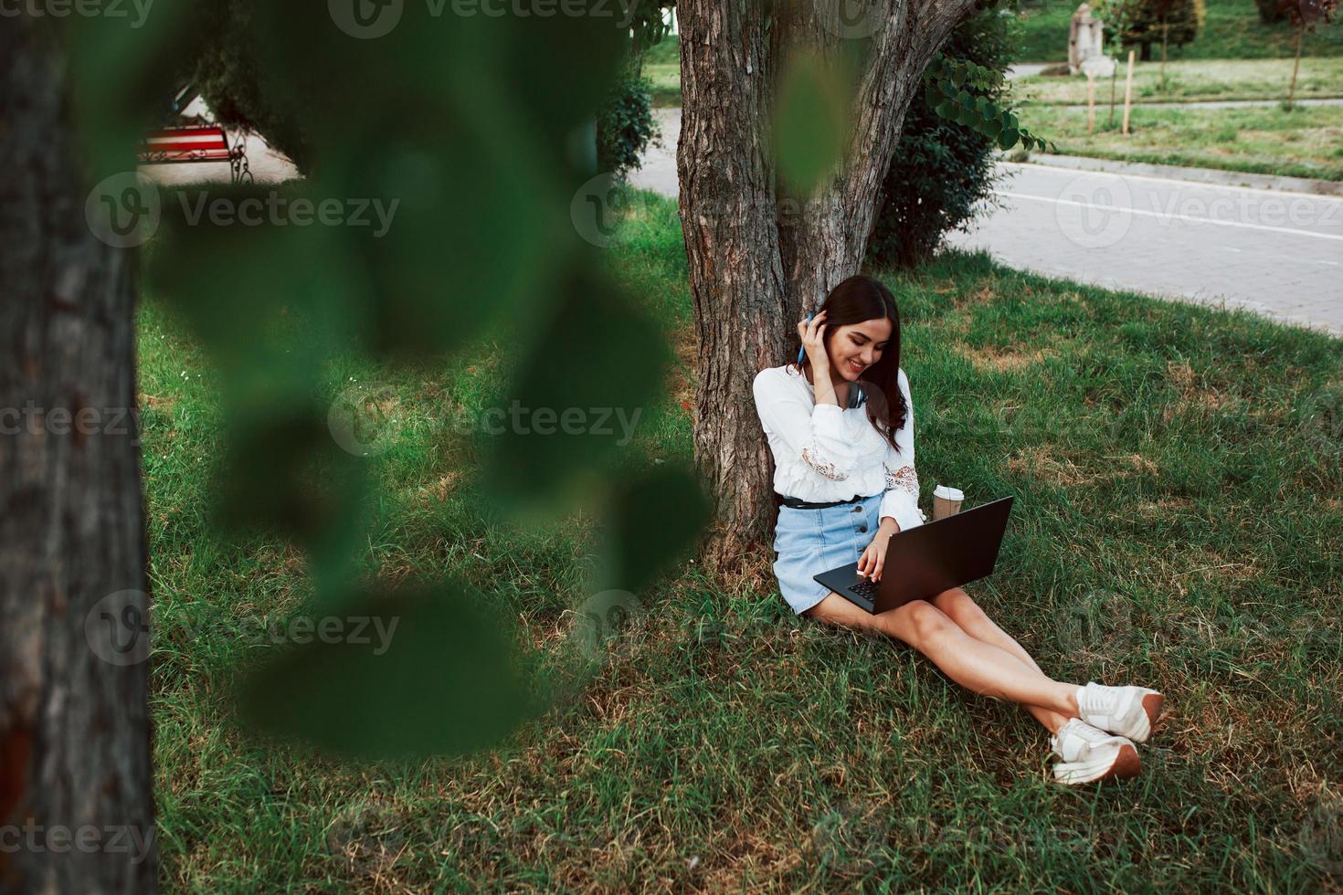 avoir de la bonne humeur. jeune femme a le week-end et s'assoit dans le parc pendant la journée photo