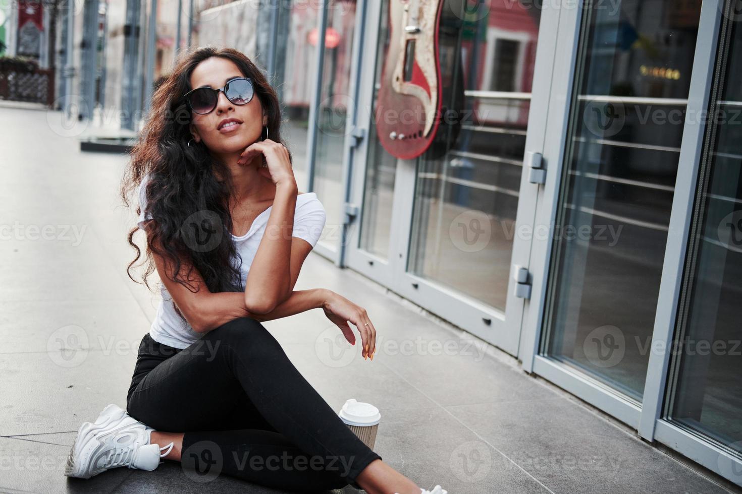 en lunettes de soleil. belle femme aux cheveux noirs bouclés passer du bon temps dans la ville pendant la journée photo